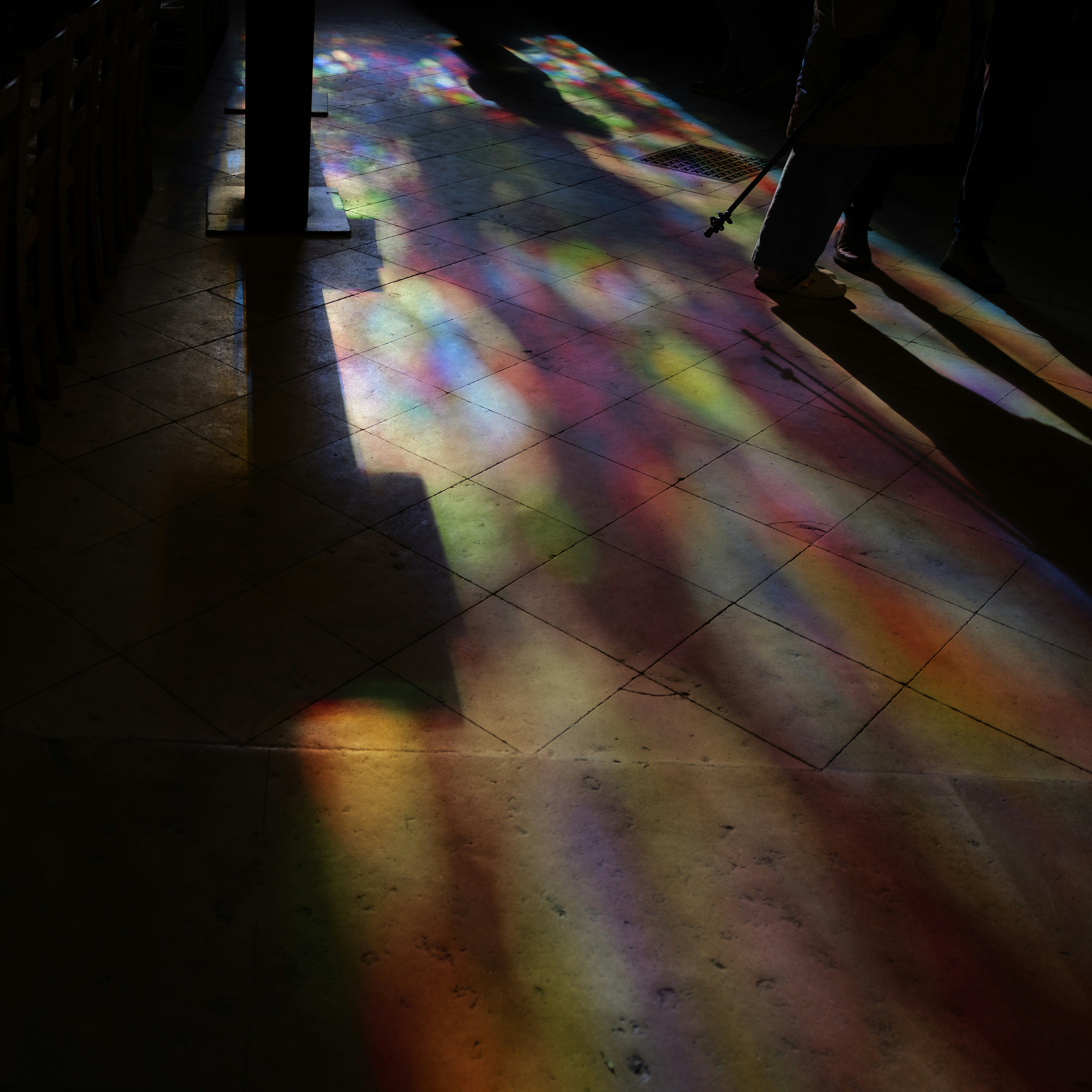 Colorful light patterns cast on a tiled floor.