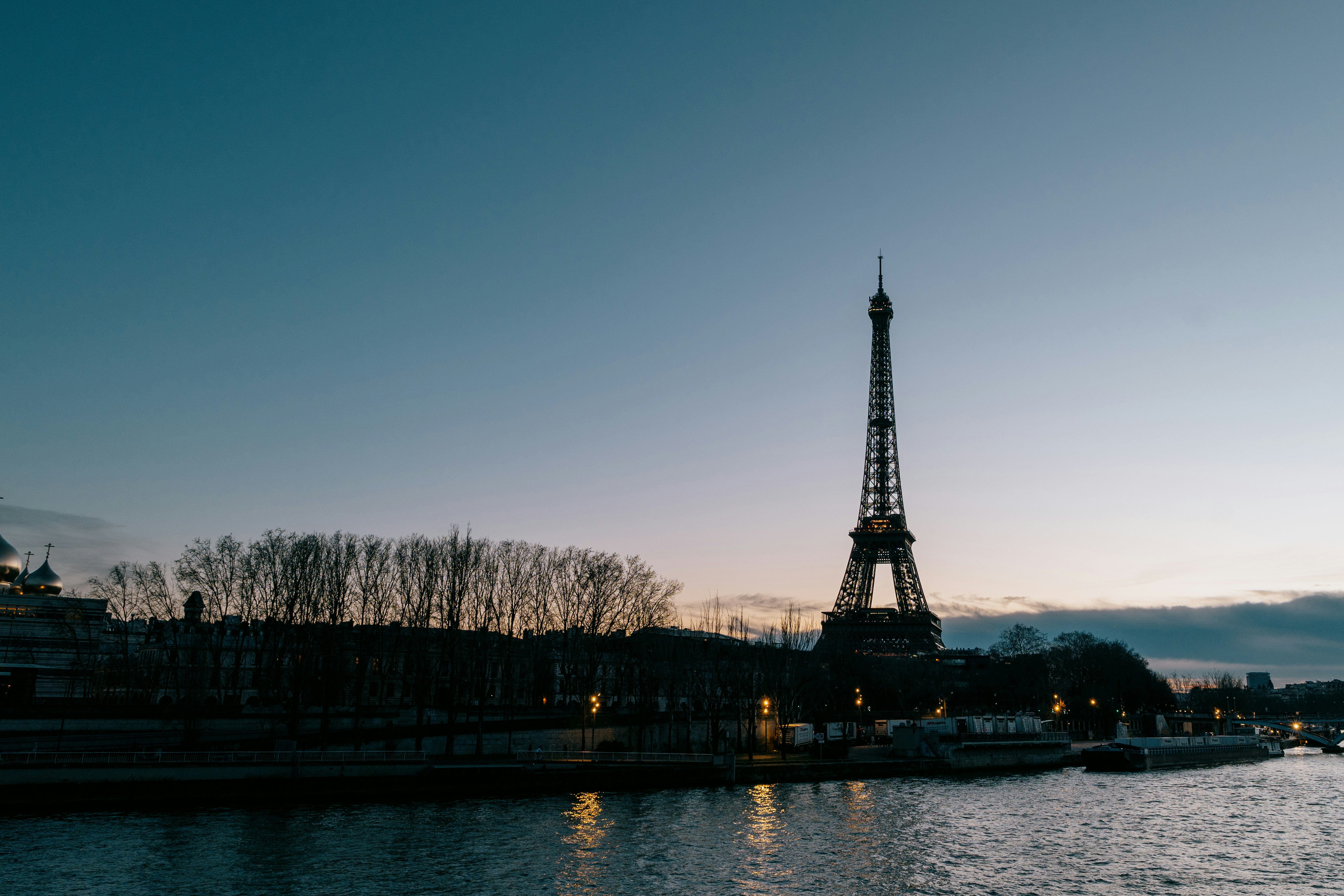 Eiffel tower silhouette at dusk over the seine river.