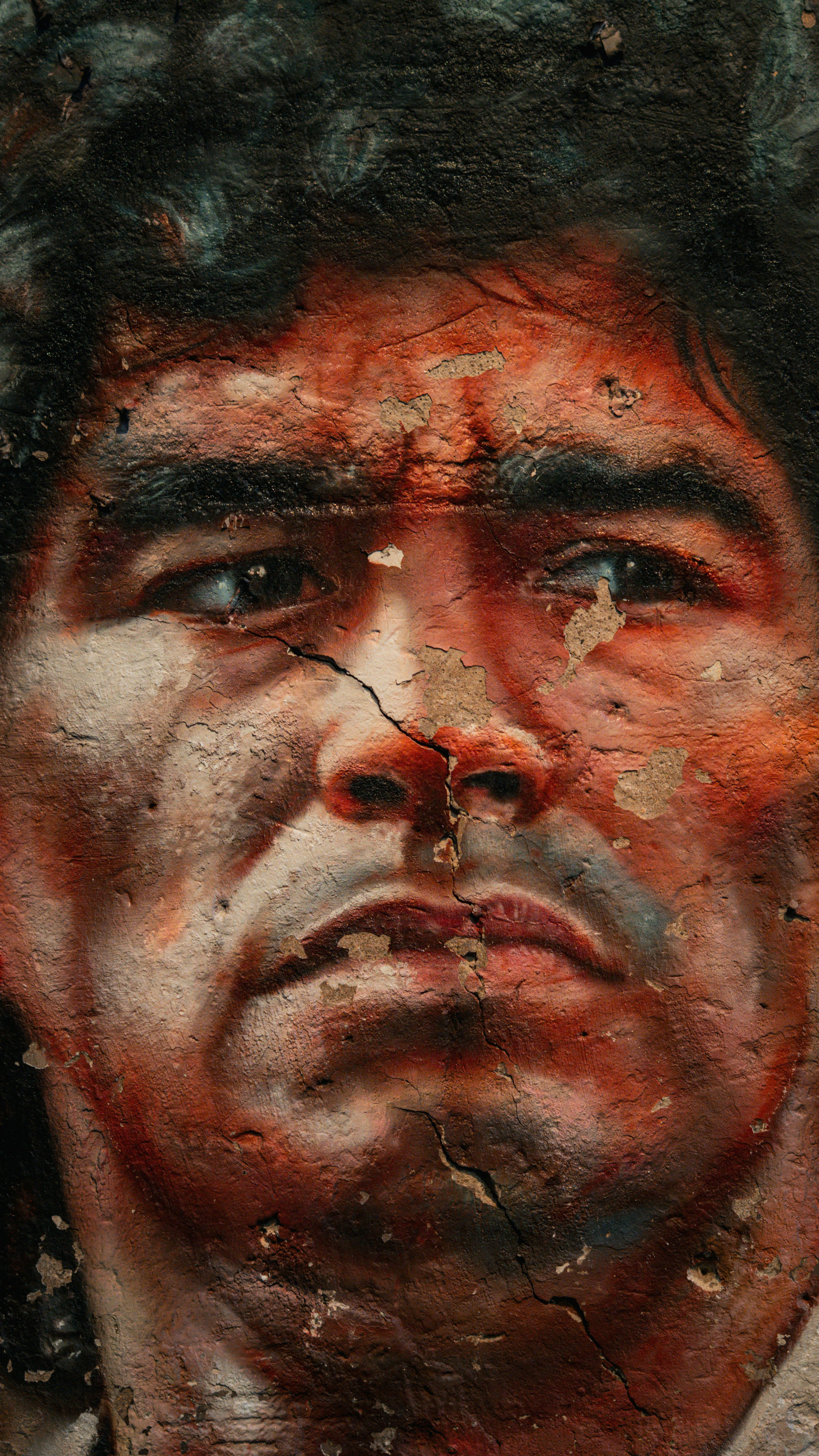 Close-up of a weathered mural of a man's face.