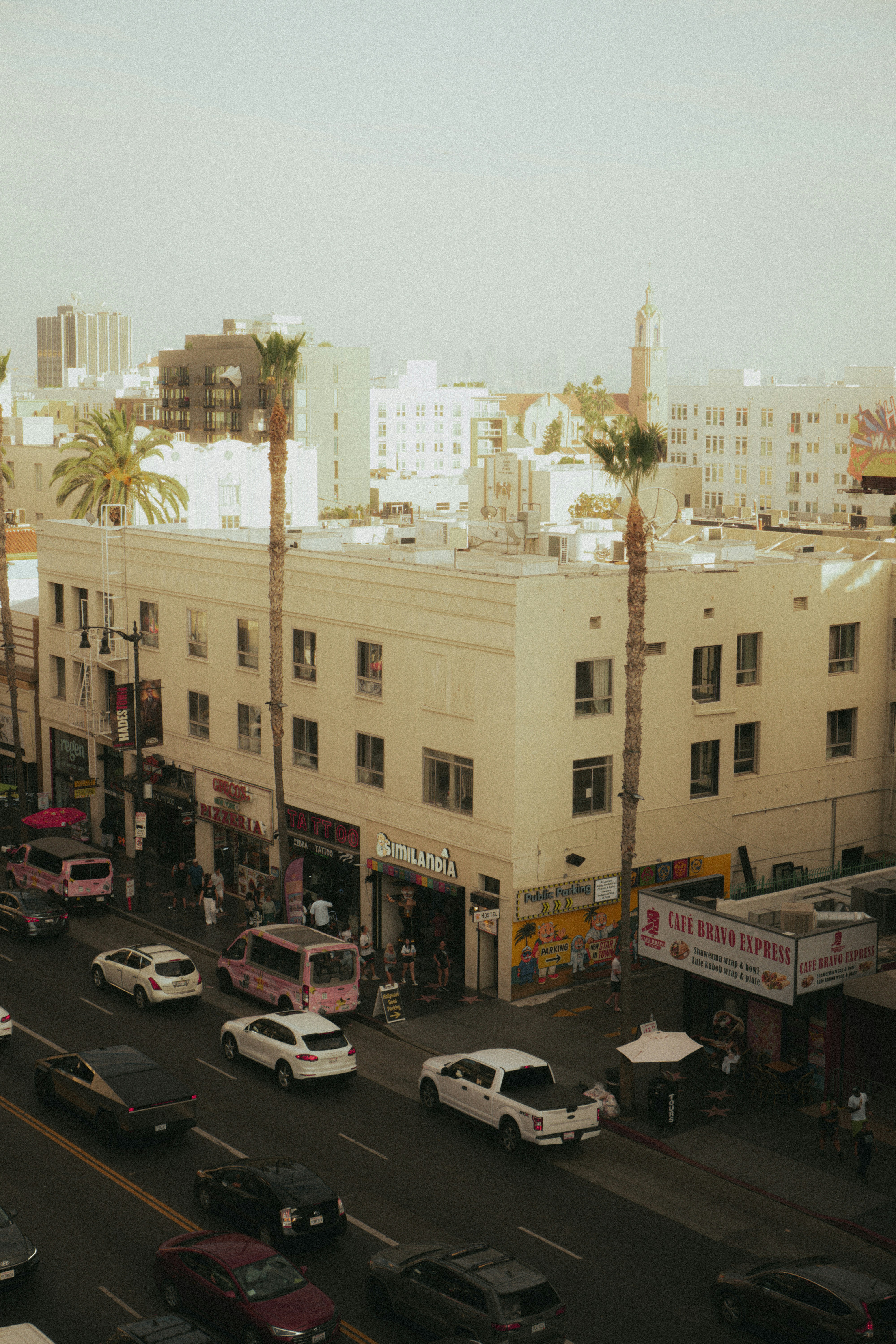Busy street with cars and palm trees in city.