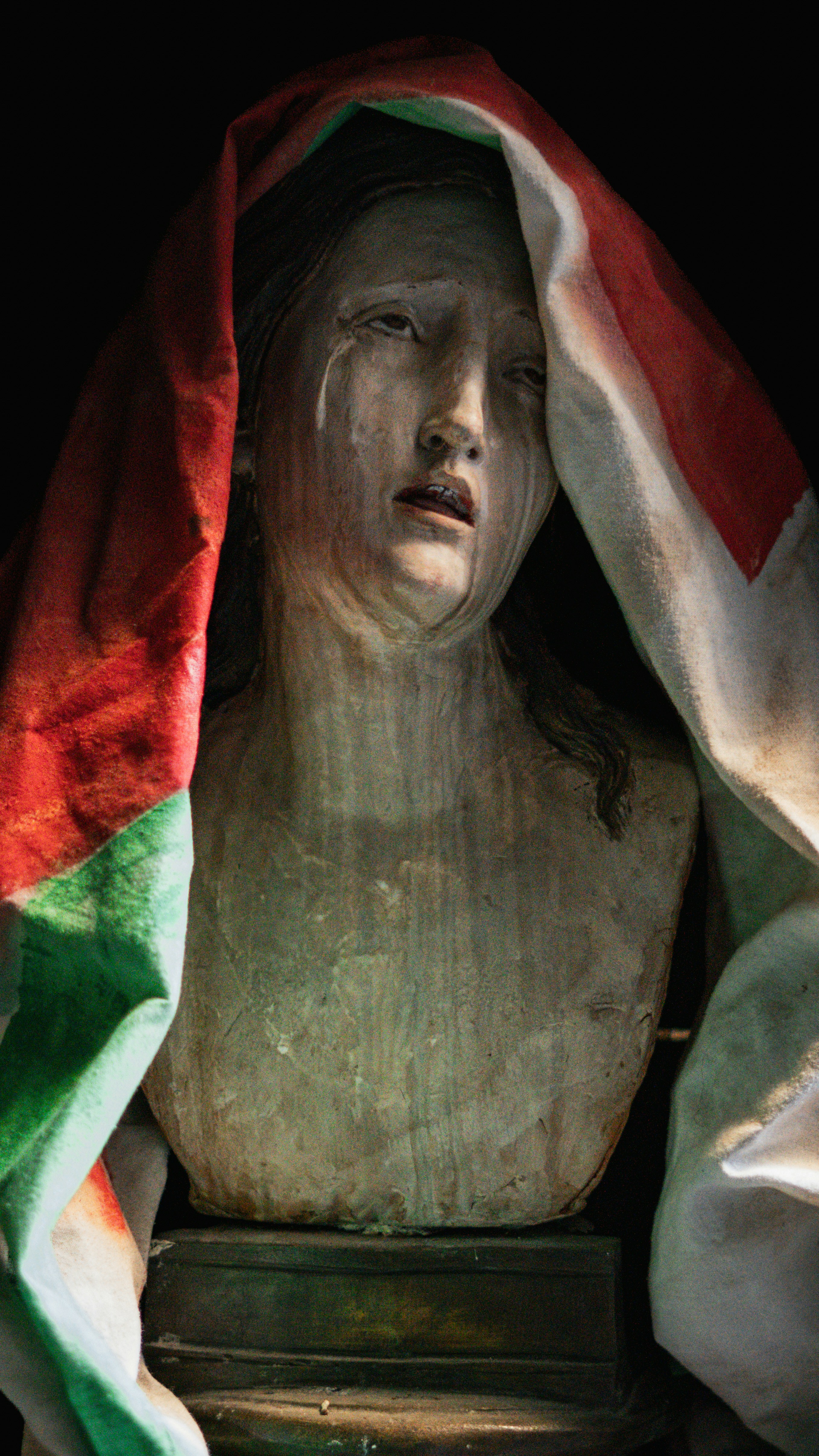 A statue of a crying woman draped in a flag.