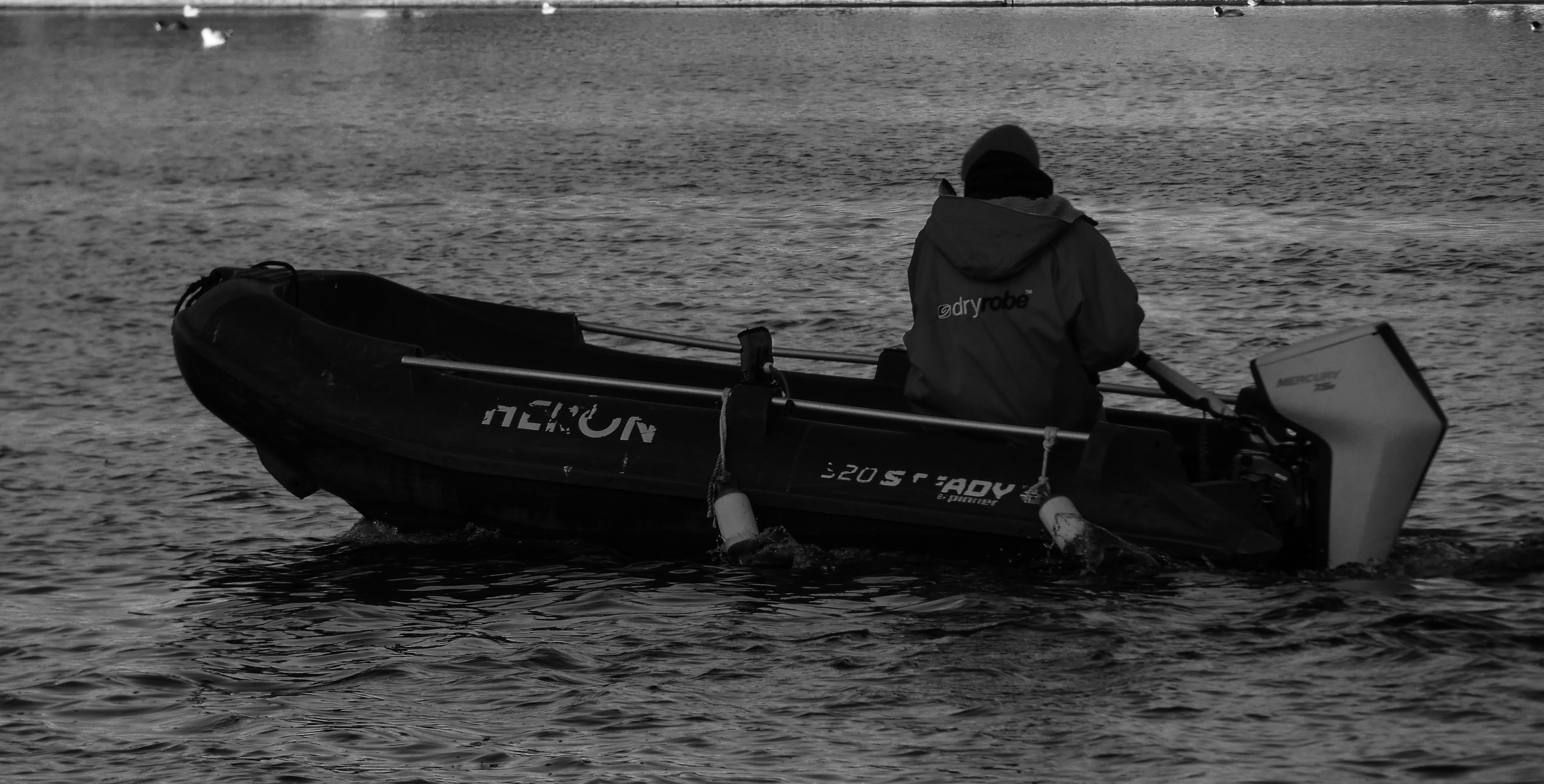 Person rowing an inflatable boat with an outboard motor.