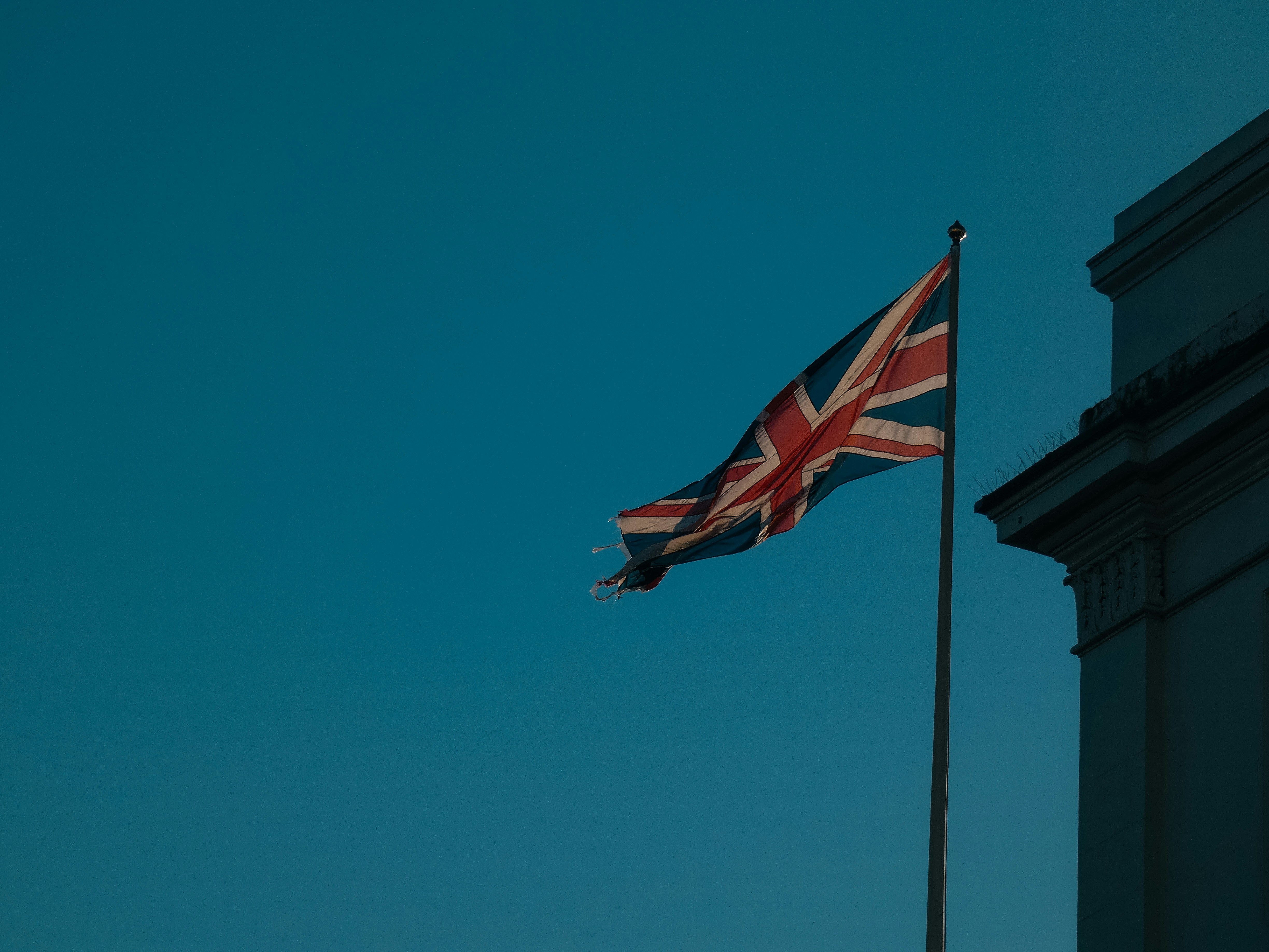 Union jack flag waving against a clear blue sky.
