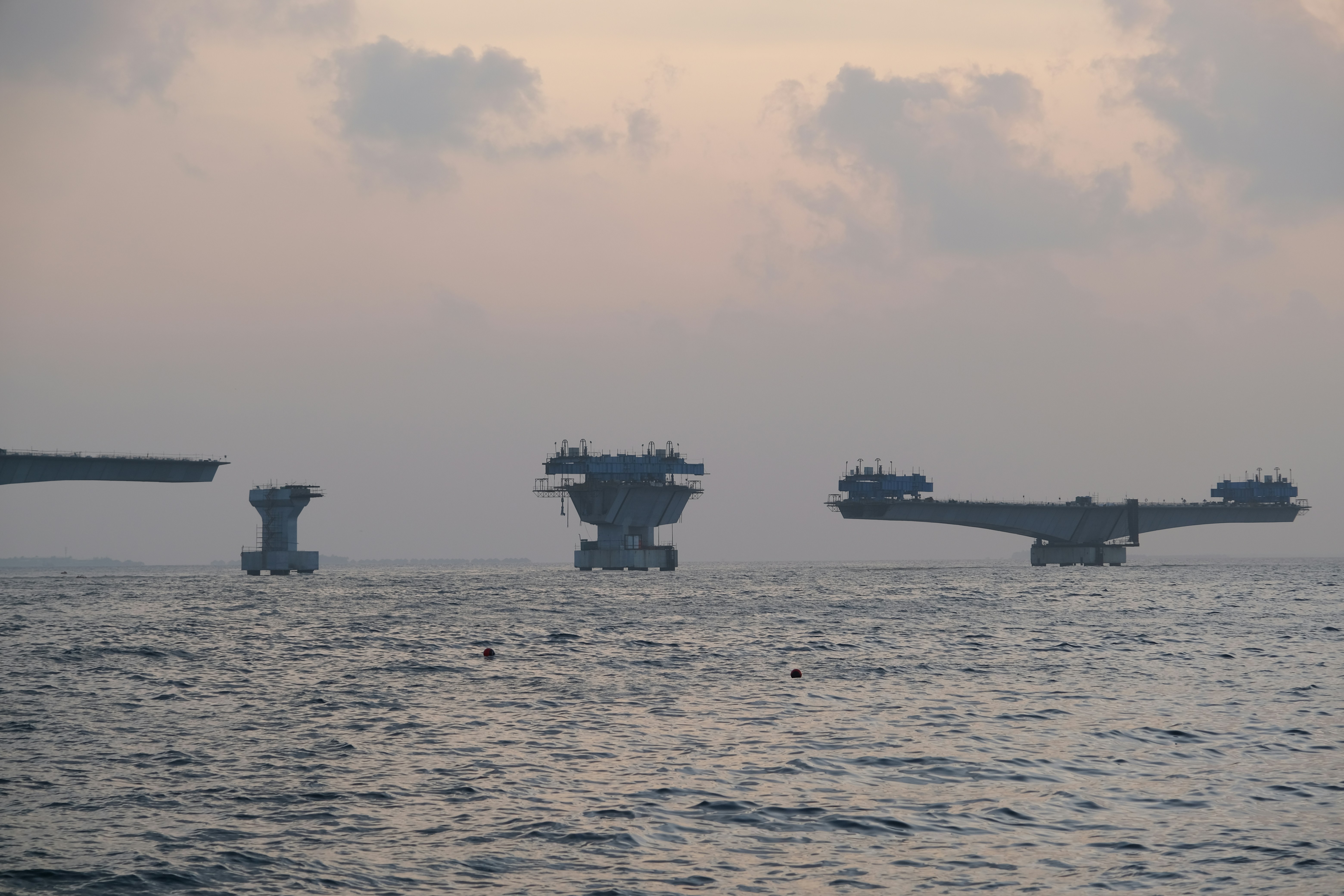 Bridge construction over the ocean at dusk
