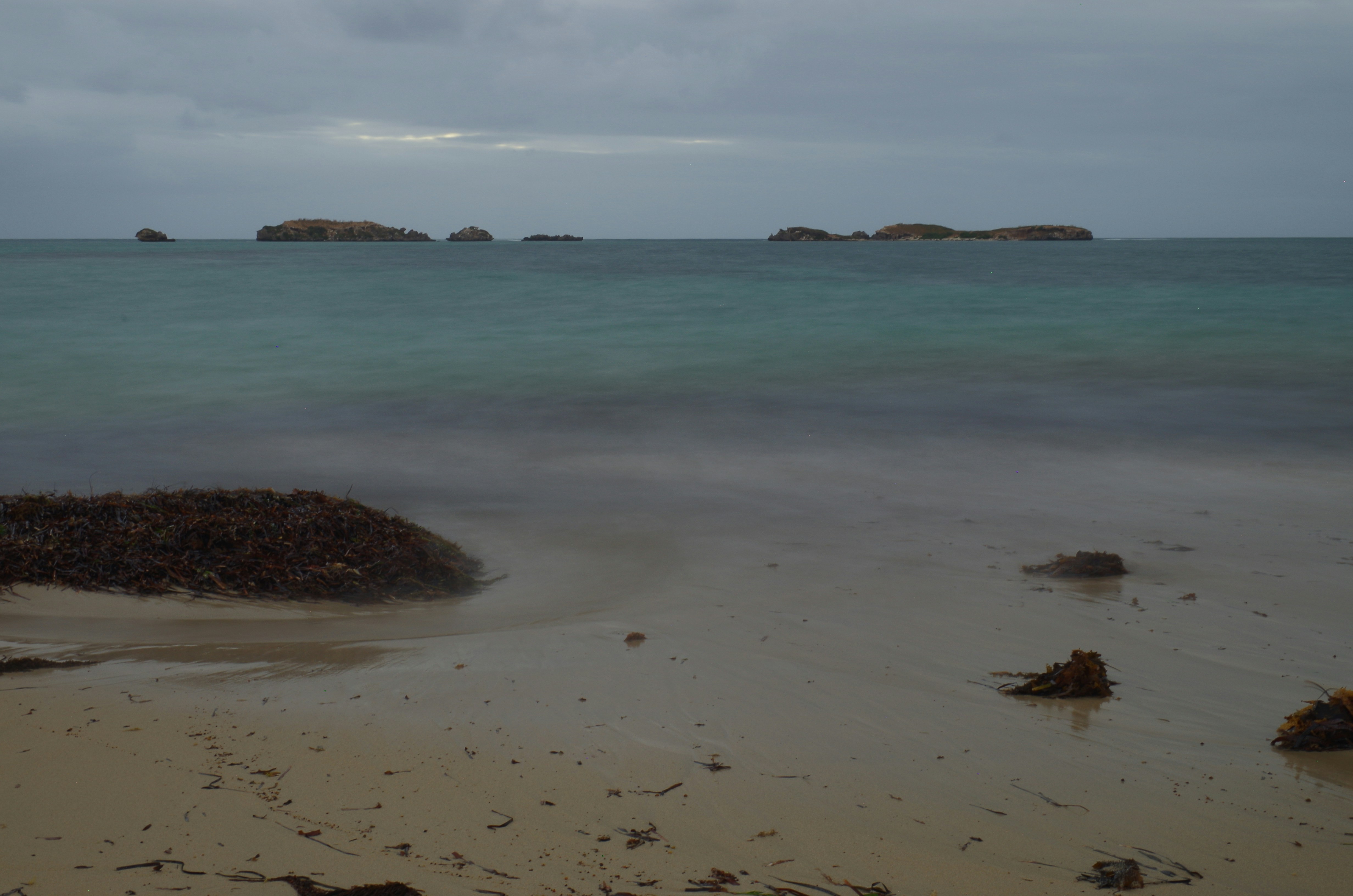 Onde dell'oceano che si infrangono su una spiaggia sabbiosa con rocce.