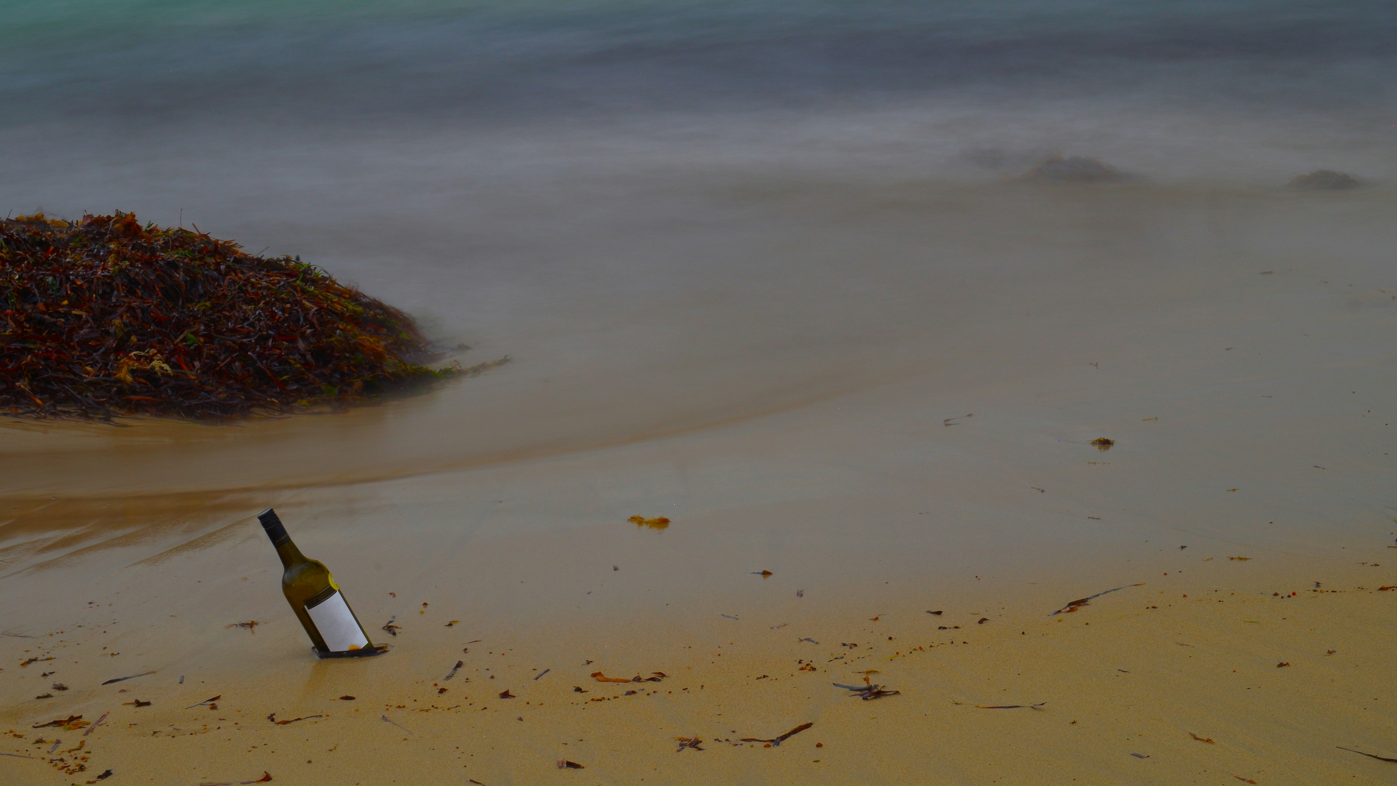Una bottiglia su una spiaggia sabbiosa con onde leggere.