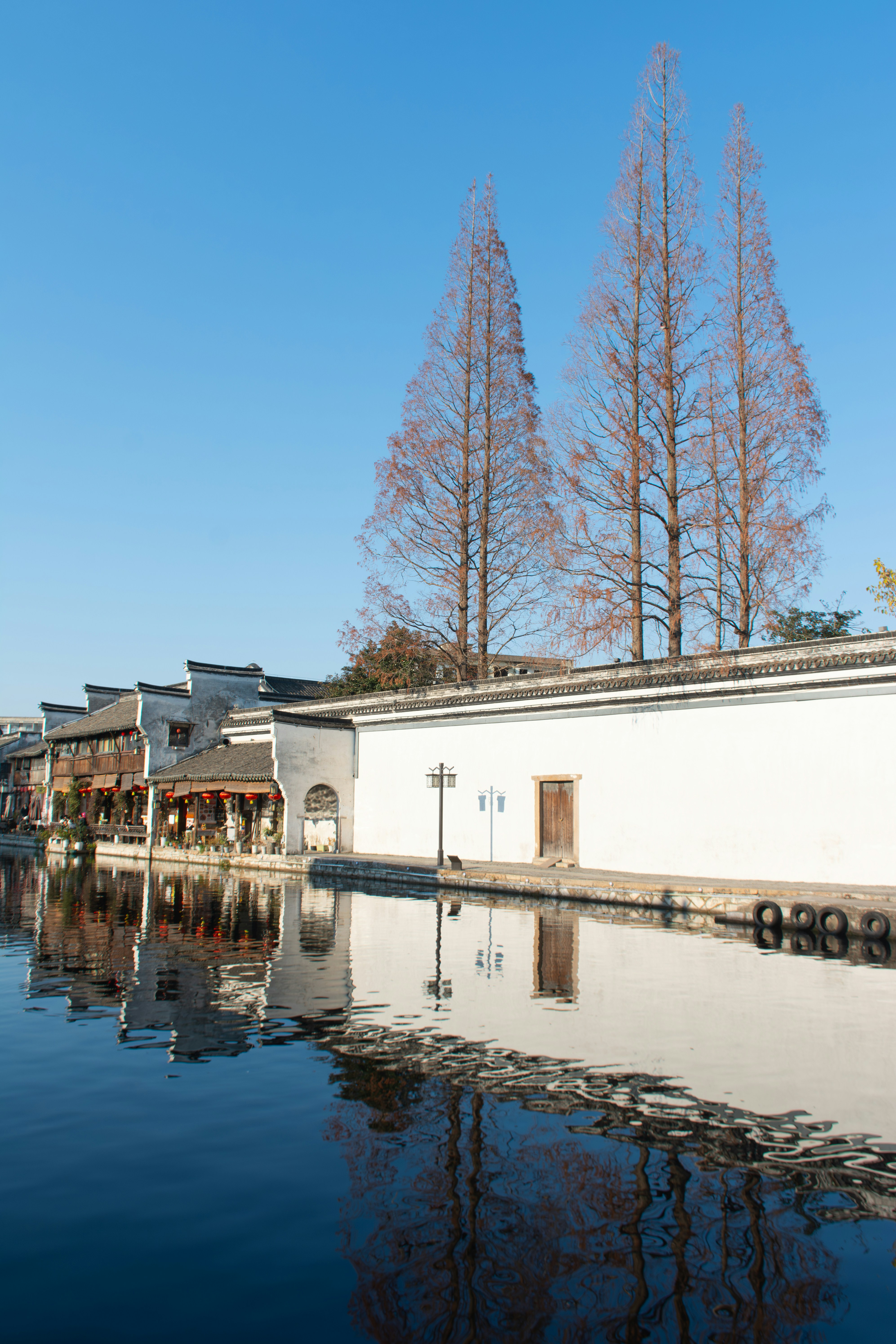 Traditionelle chinesische Gebäude säumen einen Kanal mit Spiegelungen.