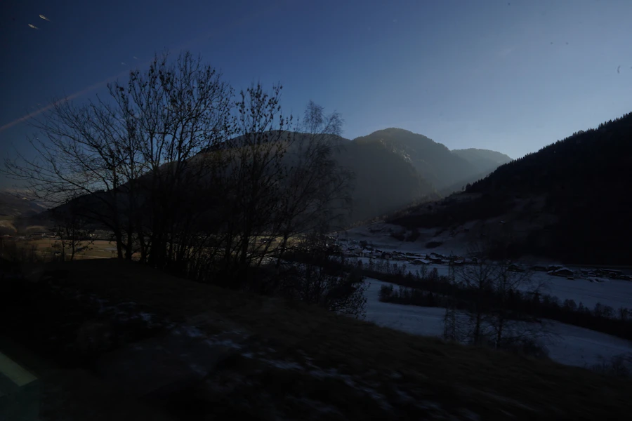 A dark, moody mountain valley at dusk