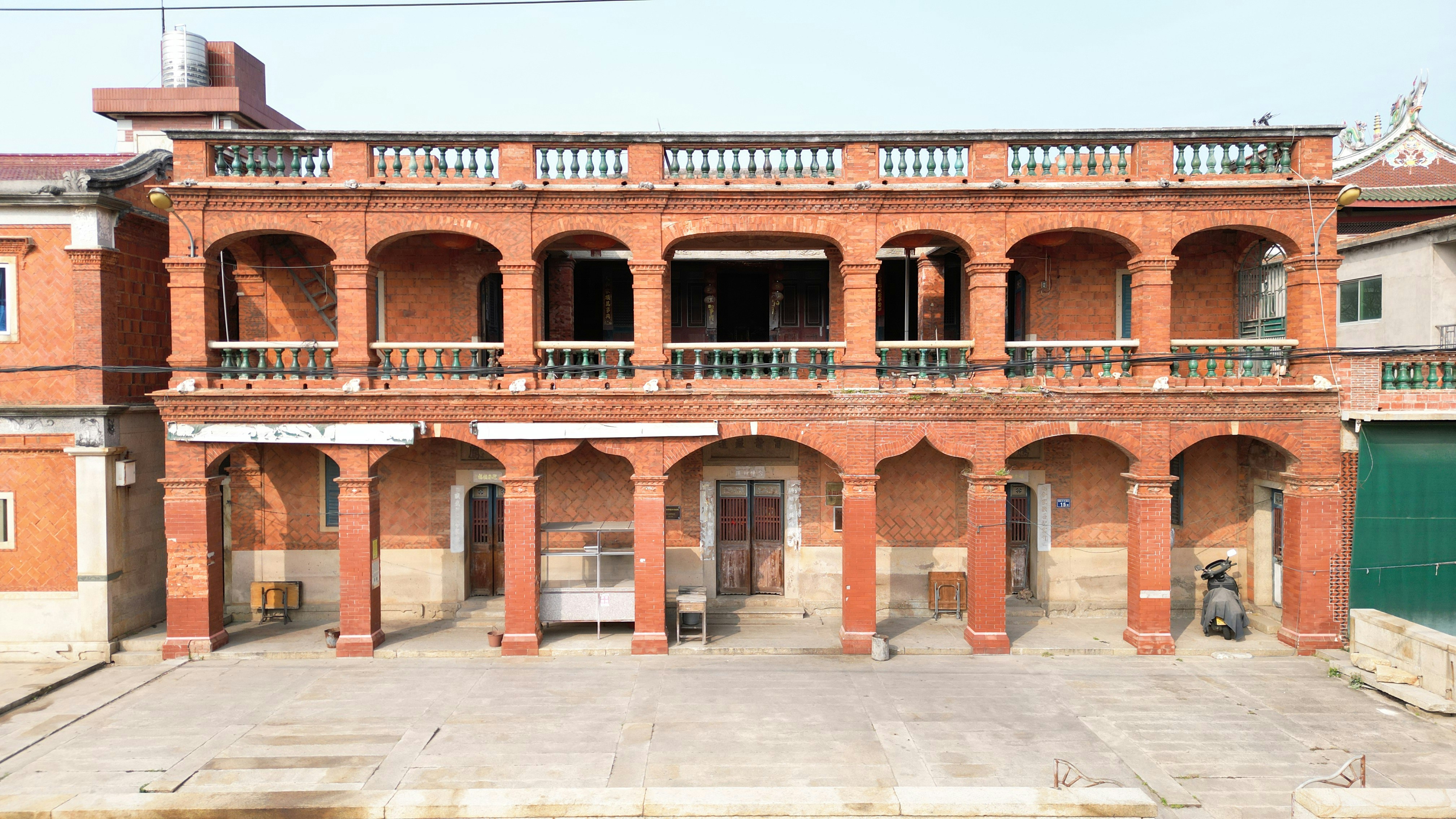 Two-story red brick building with arched doorways and balconies