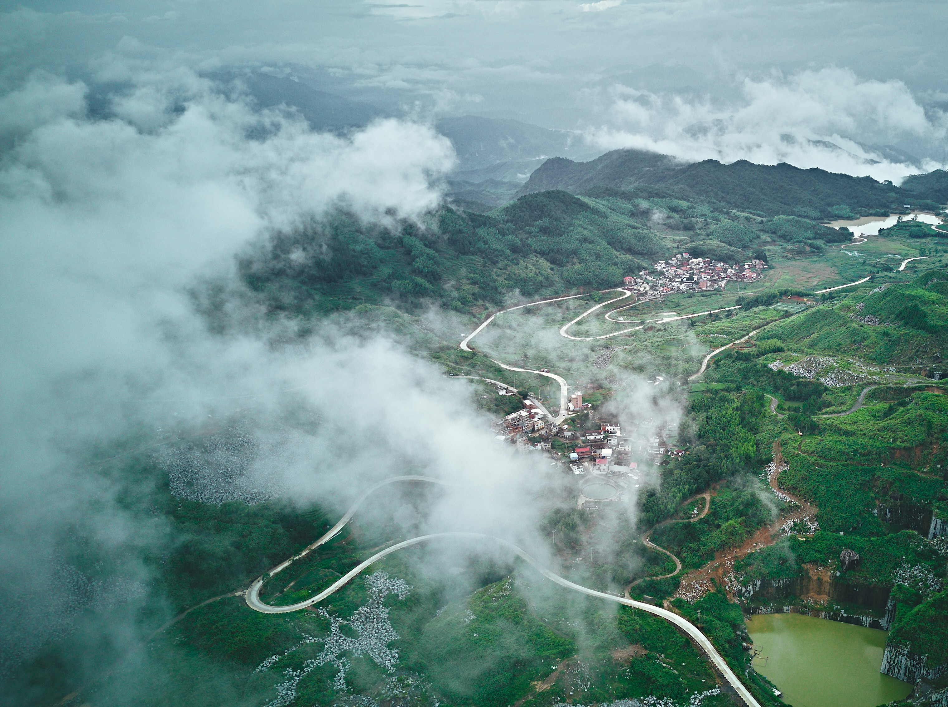 Carretera serpenteante a través de montañas verdes y brumosas con aldeas