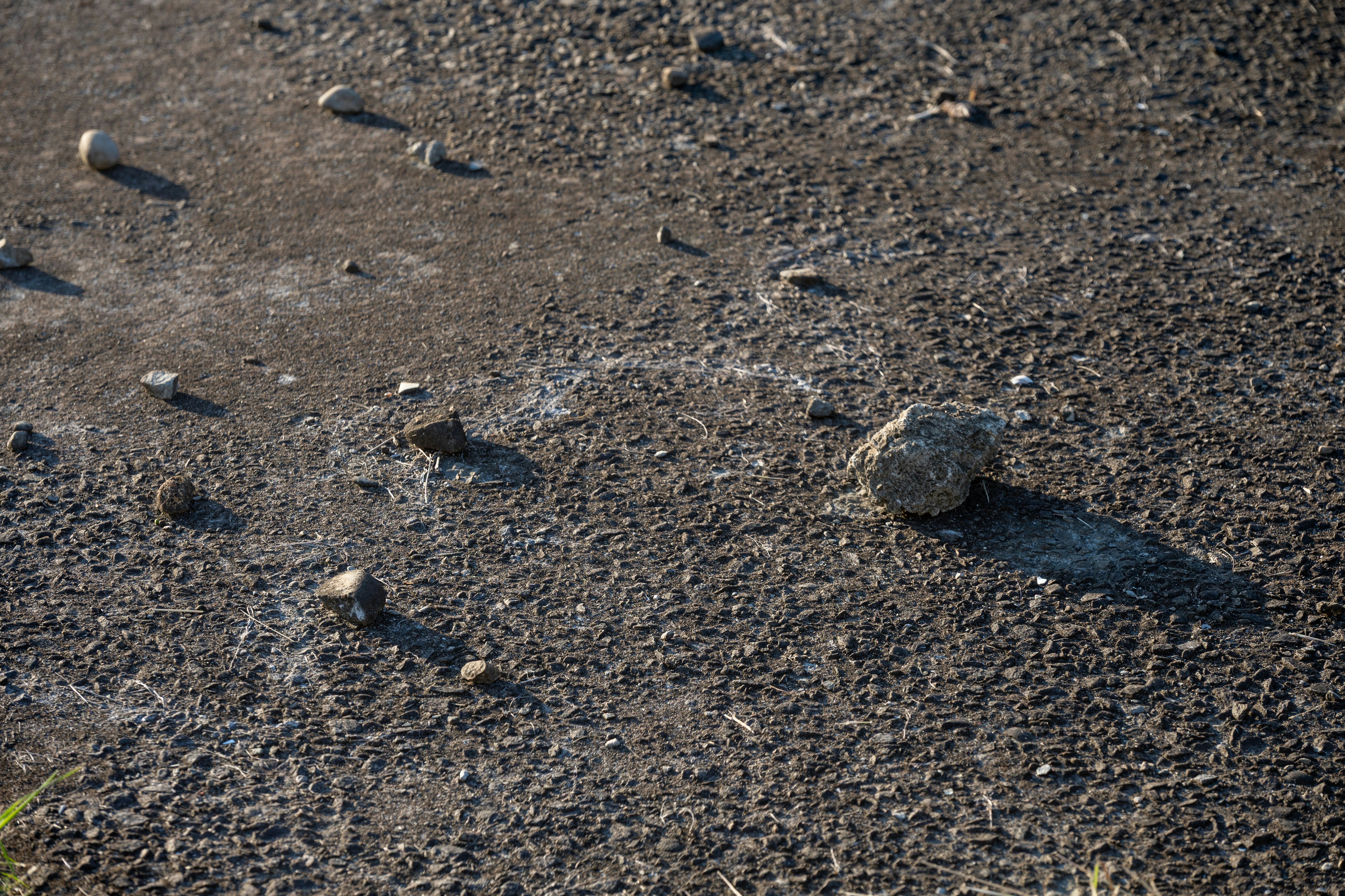 Kleine Steine lagen auf einer dunklen, rauen Oberfläche verstreut.