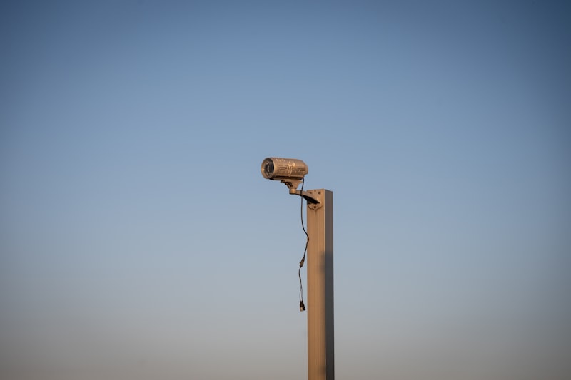 Security camera on pole against blue sky