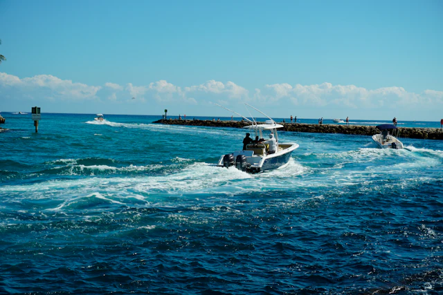 Small boats working their way out through an inlet beside a rock jetty