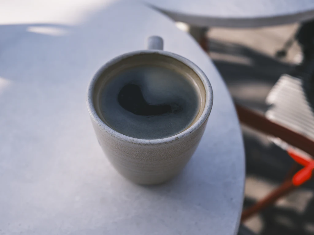 Café noir dans une tasse en céramique sur une table claire ; teneur en caféine inconnue