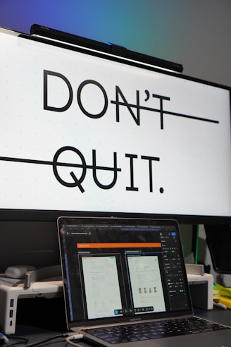 Monitor displays 'don't quit.' with laptop below.