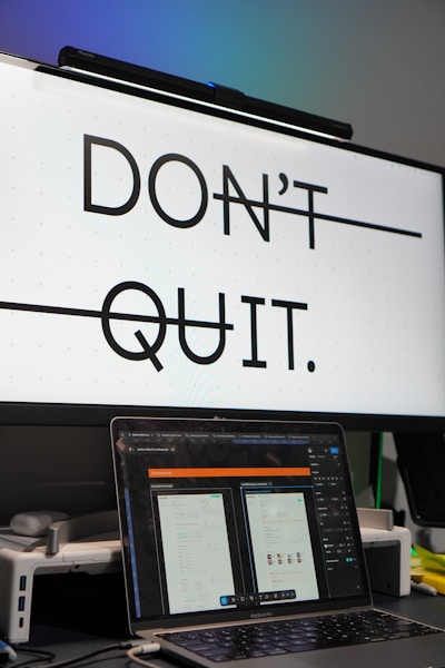 Monitor displays 'don't quit.' with laptop below.