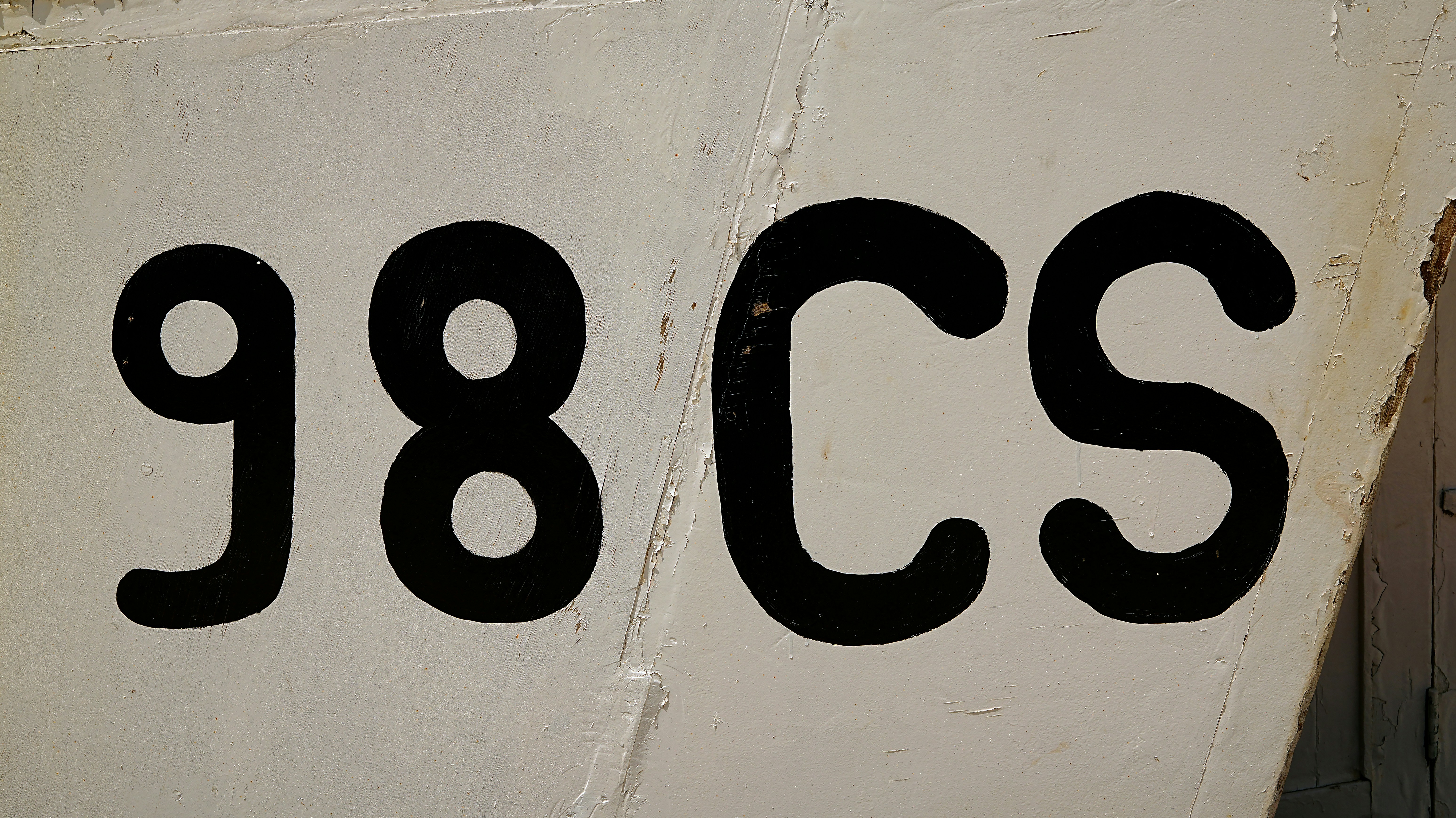Black numbers 98 and letters cs on white surface