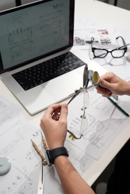 Hands measuring eyeglasses with calipers on desk