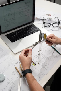Hands measuring eyeglasses with calipers on desk