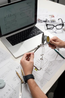 Hands measuring eyeglasses with calipers on desk