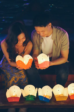 Couple holding illuminated lanterns at night