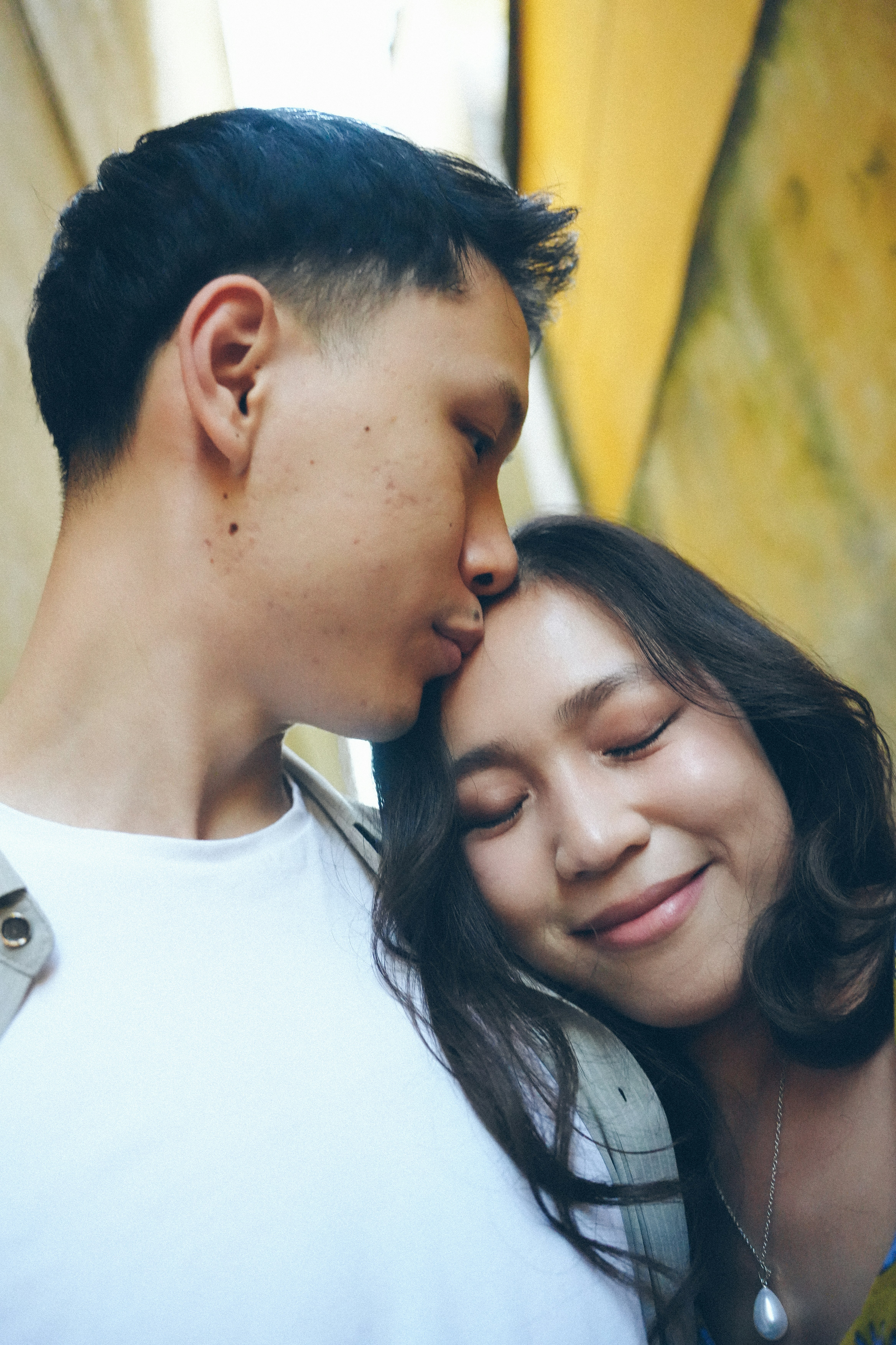 Man kisses woman's forehead with eyes closed