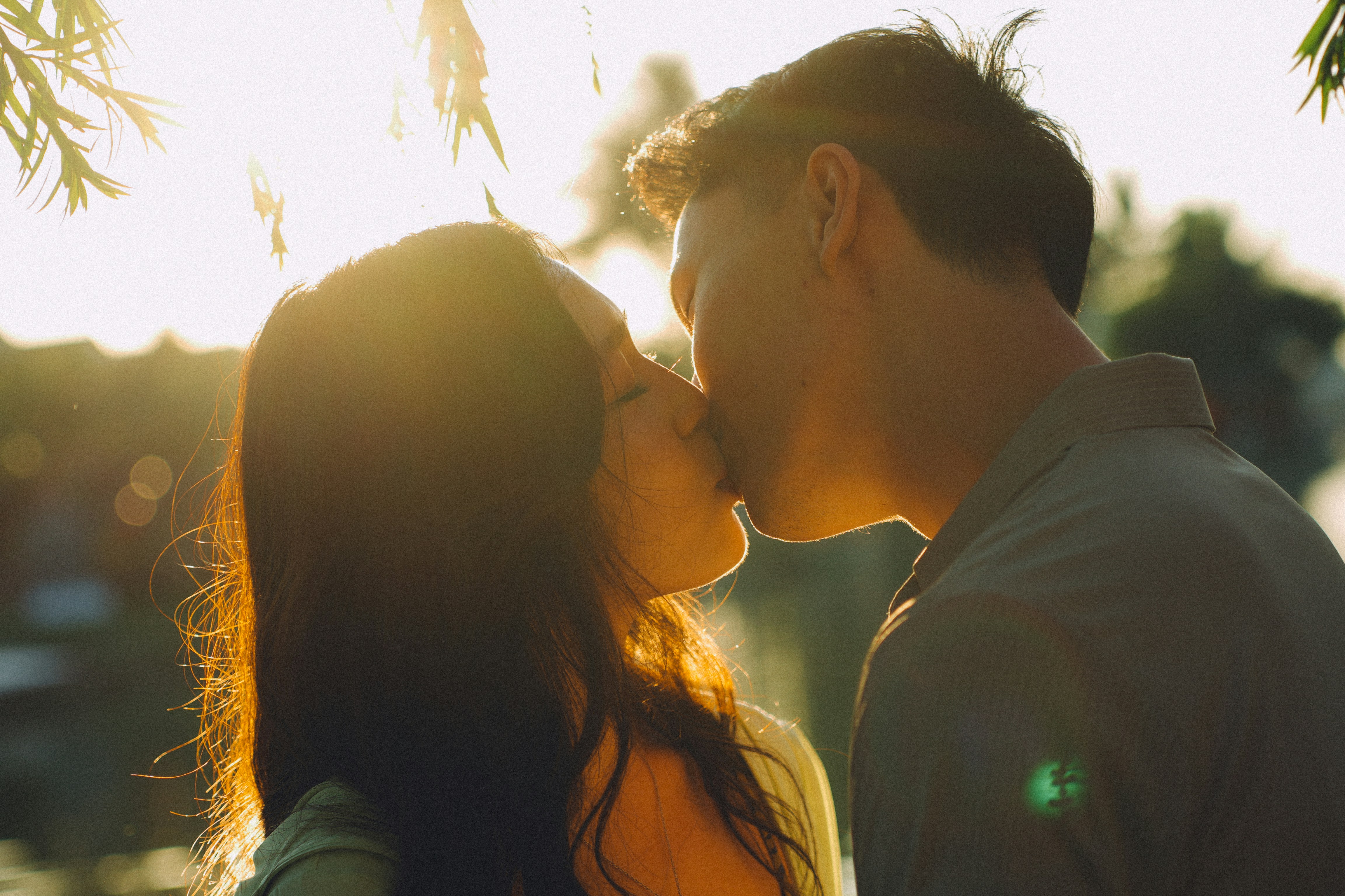 Couple kissing during golden hour with sun flare