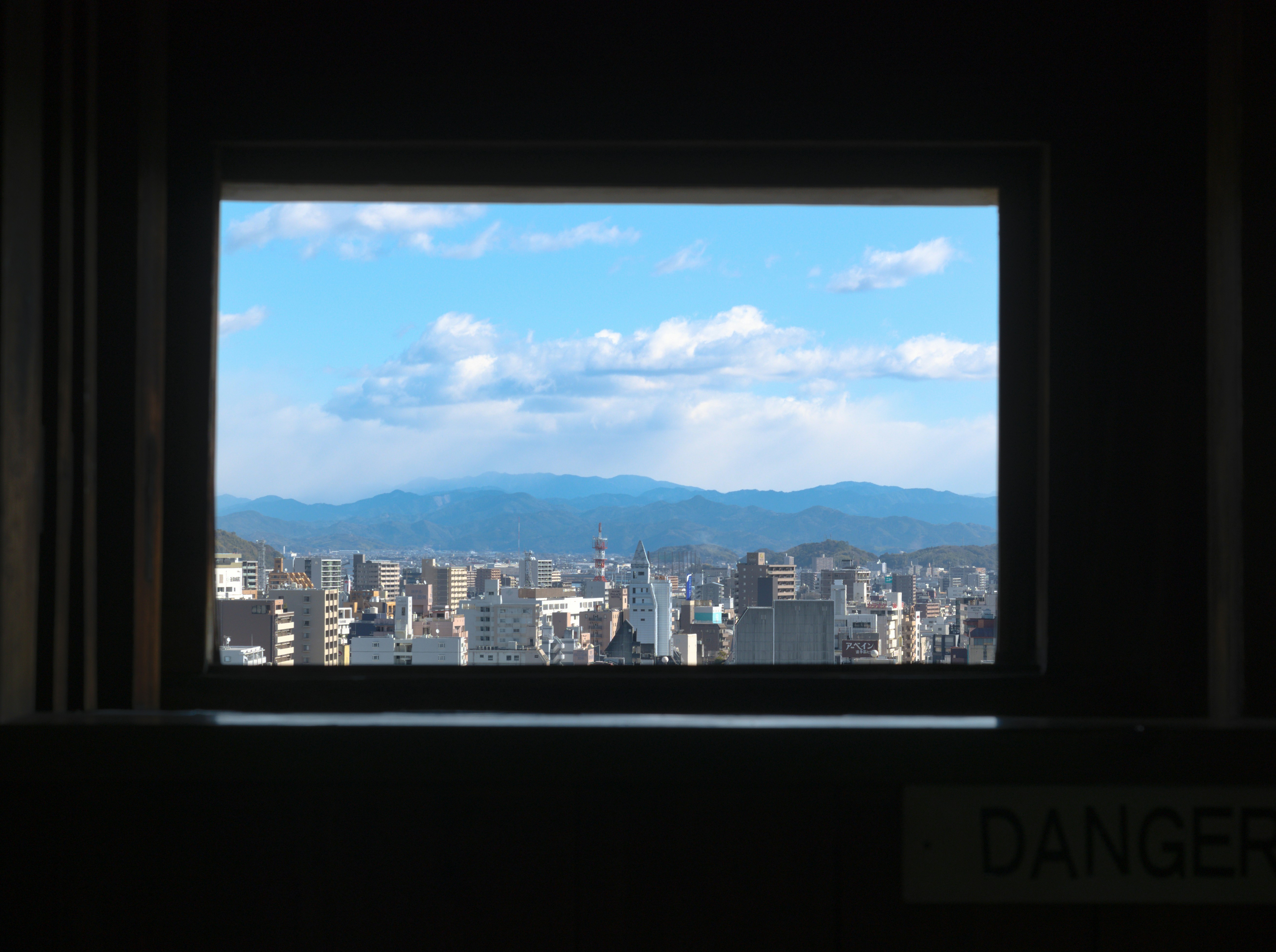 City skyline with mountains under a cloudy blue sky.