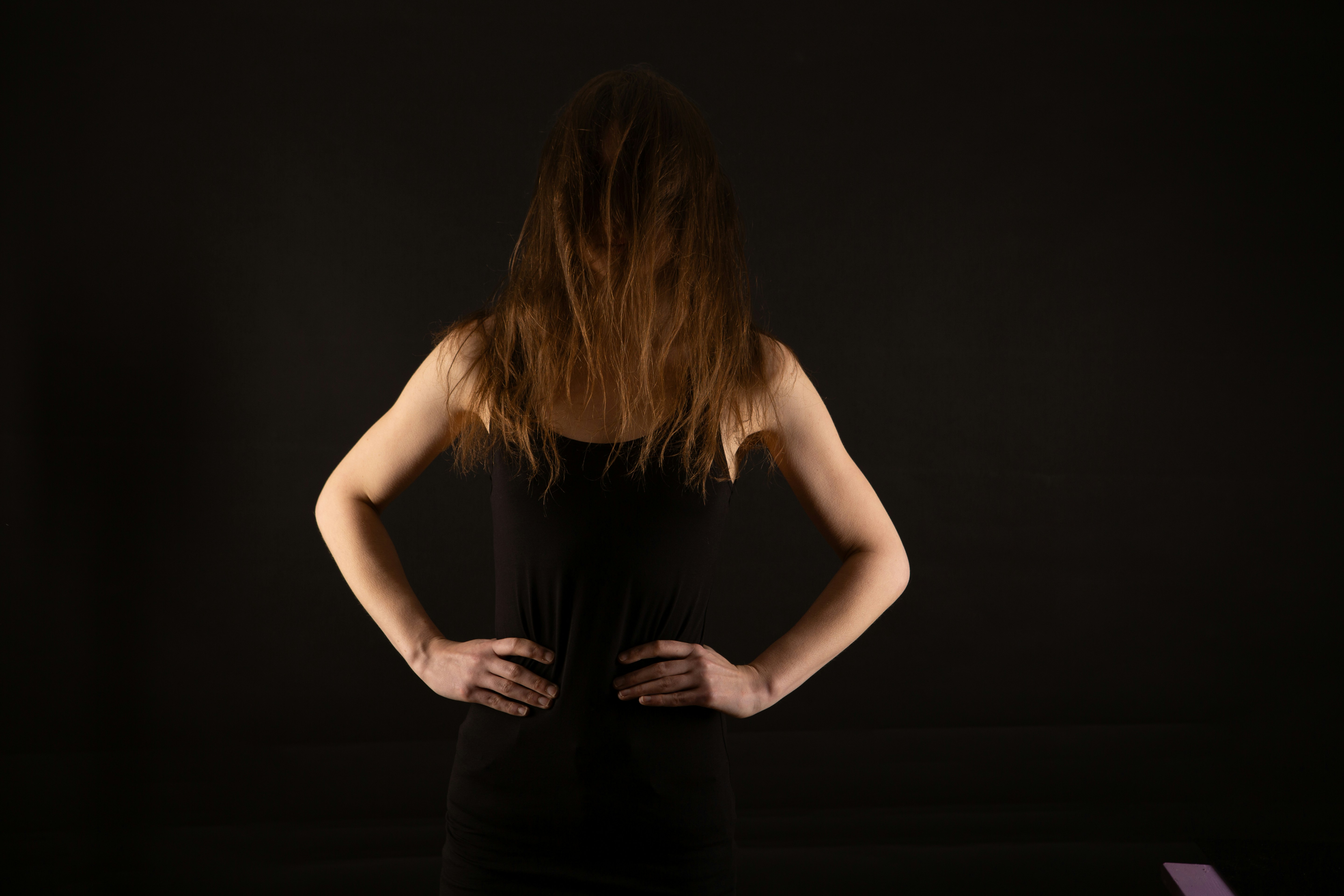 Woman with hands on hips against black background