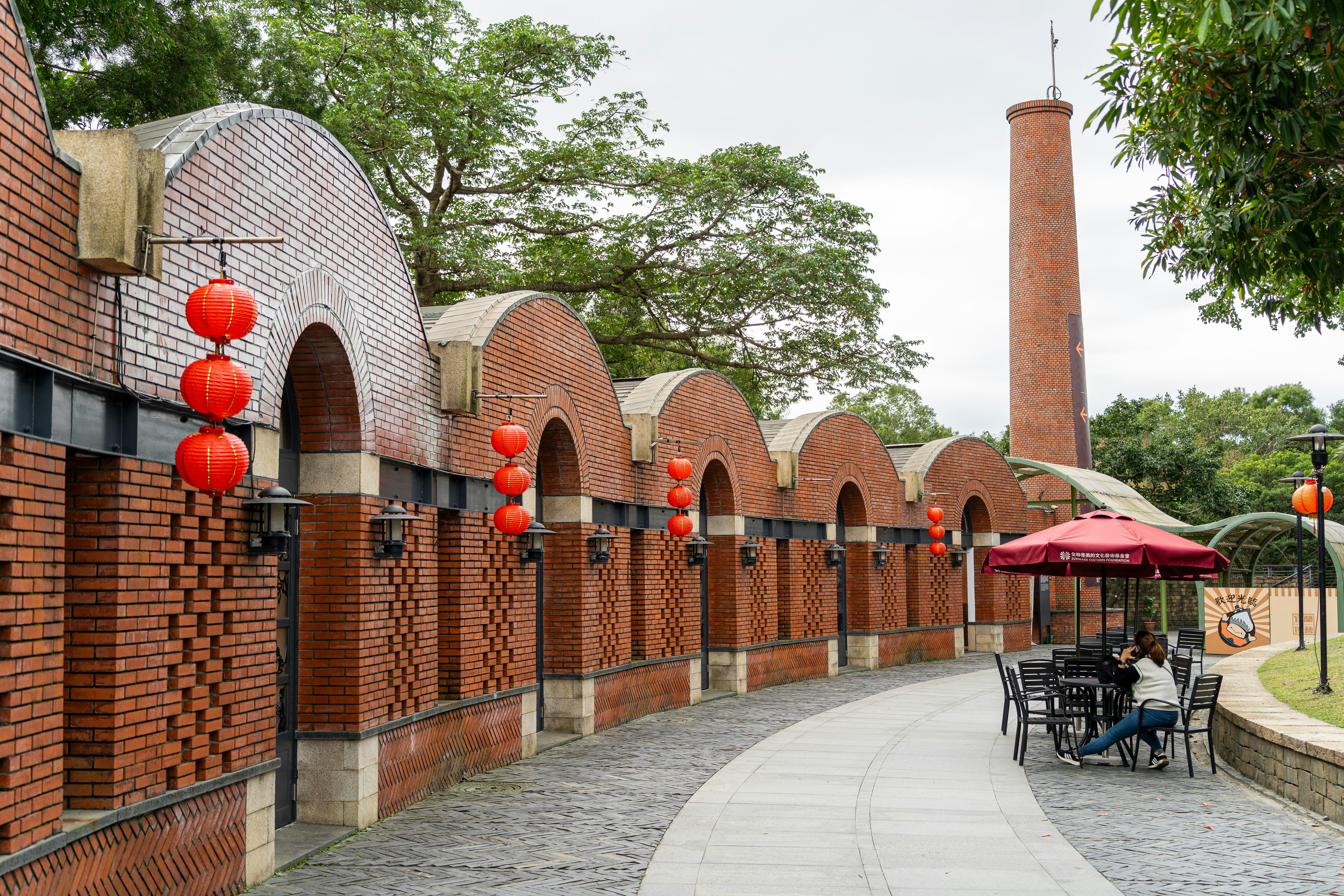 Brick building with arched windows and a tall chimney.