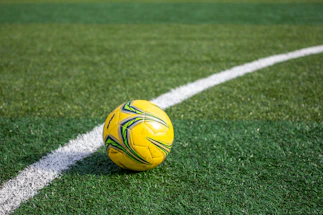A yellow soccer ball rests on the green field.