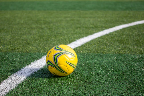 A yellow soccer ball rests on the green field.