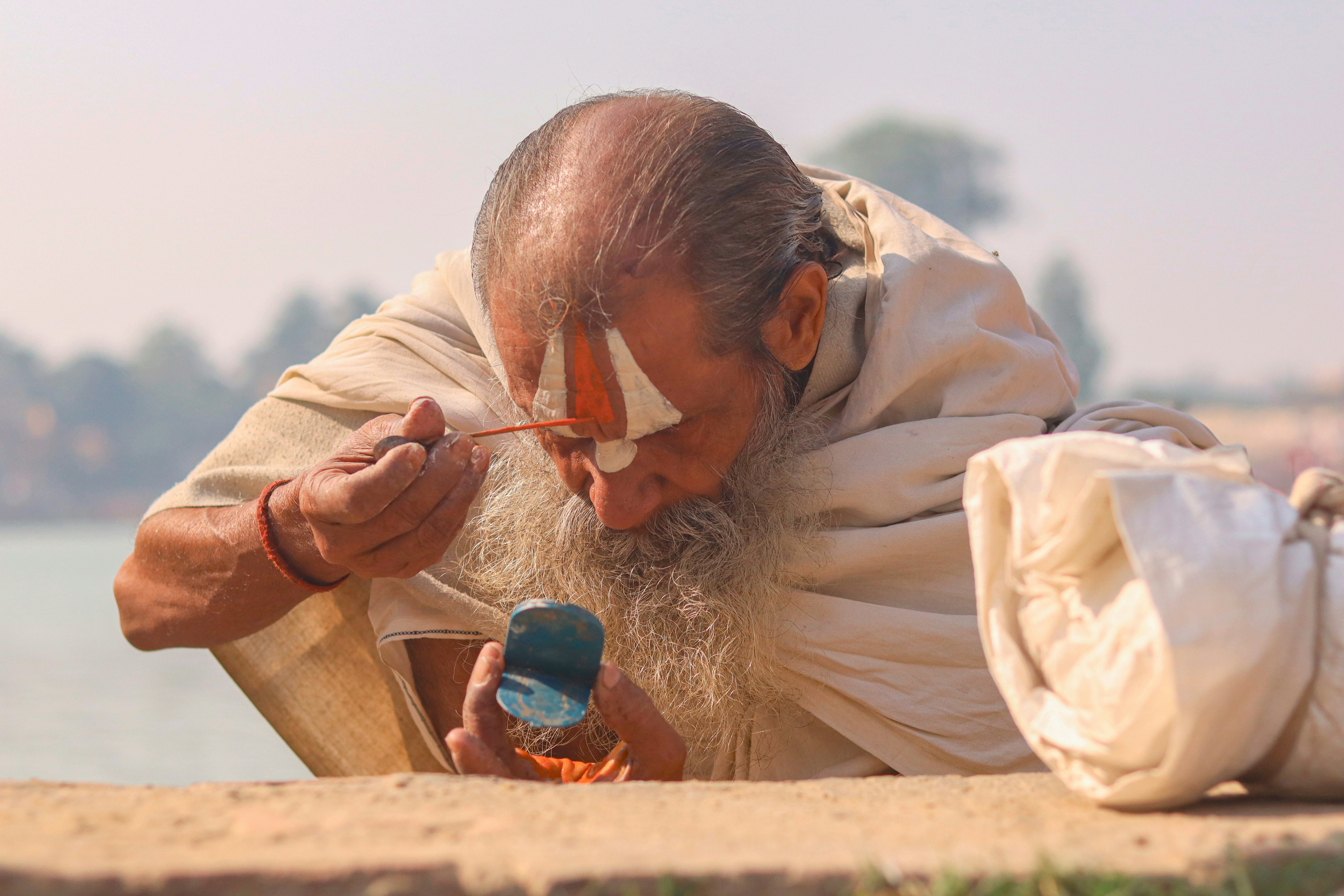 Elderly man with religious markings applying makeup