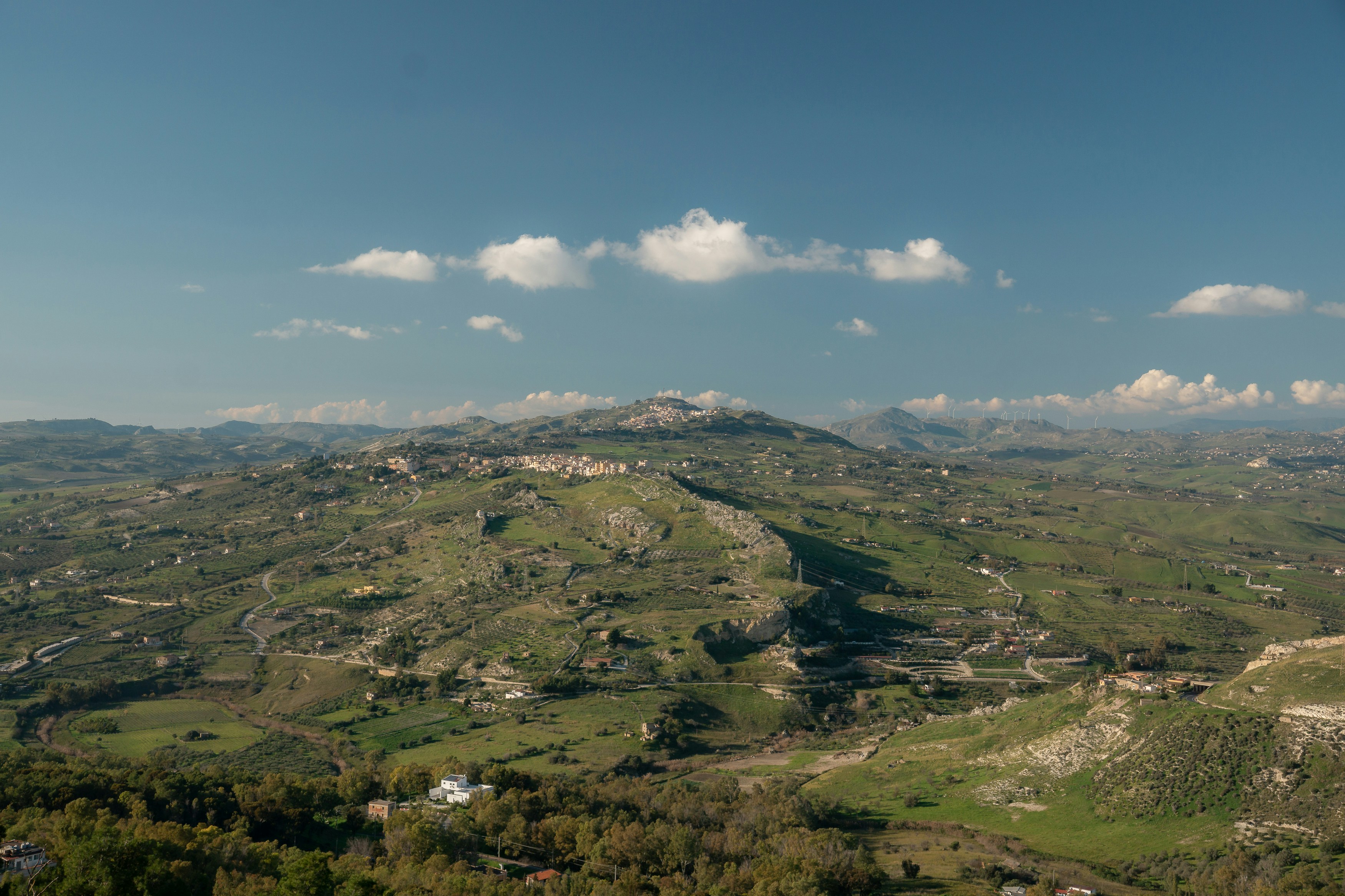 A vast green landscape with rolling hills and a town.