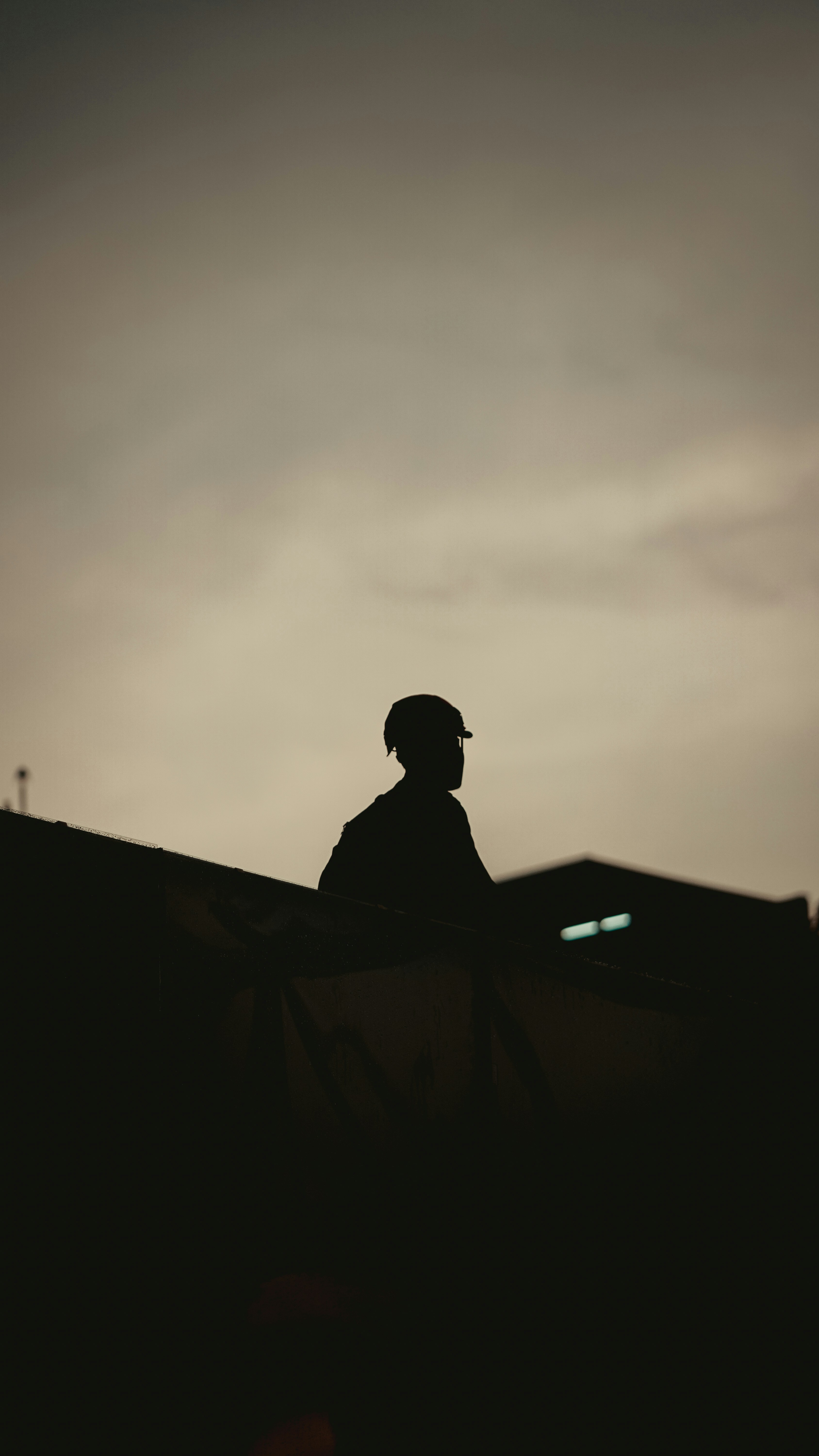 Silhouette of a person wearing a hard hat at dusk.