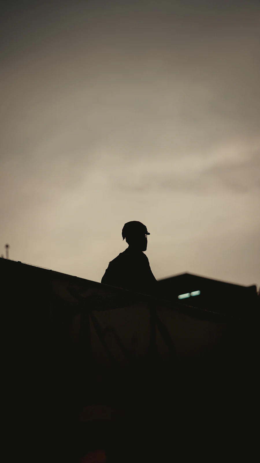 Silhouette d'un intervenant casqué sur un site industriel au crépuscule