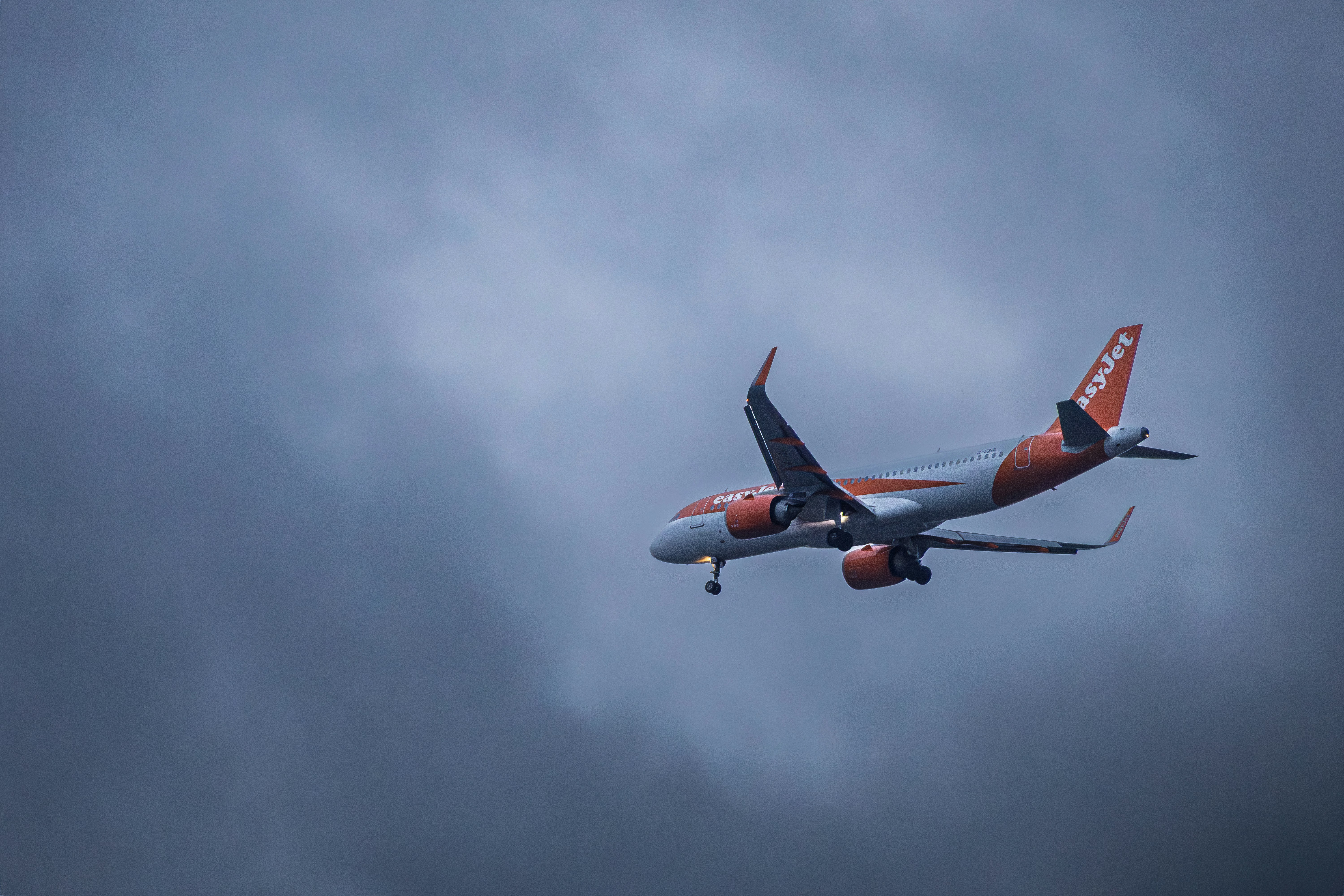 An orange and gray airplane flying through dark clouds