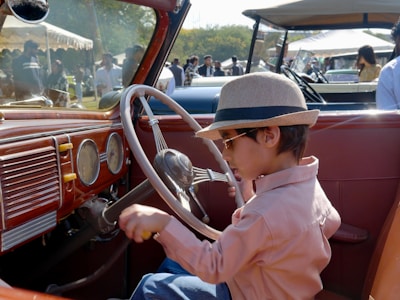 Young boy wearing hat sits in vintage car