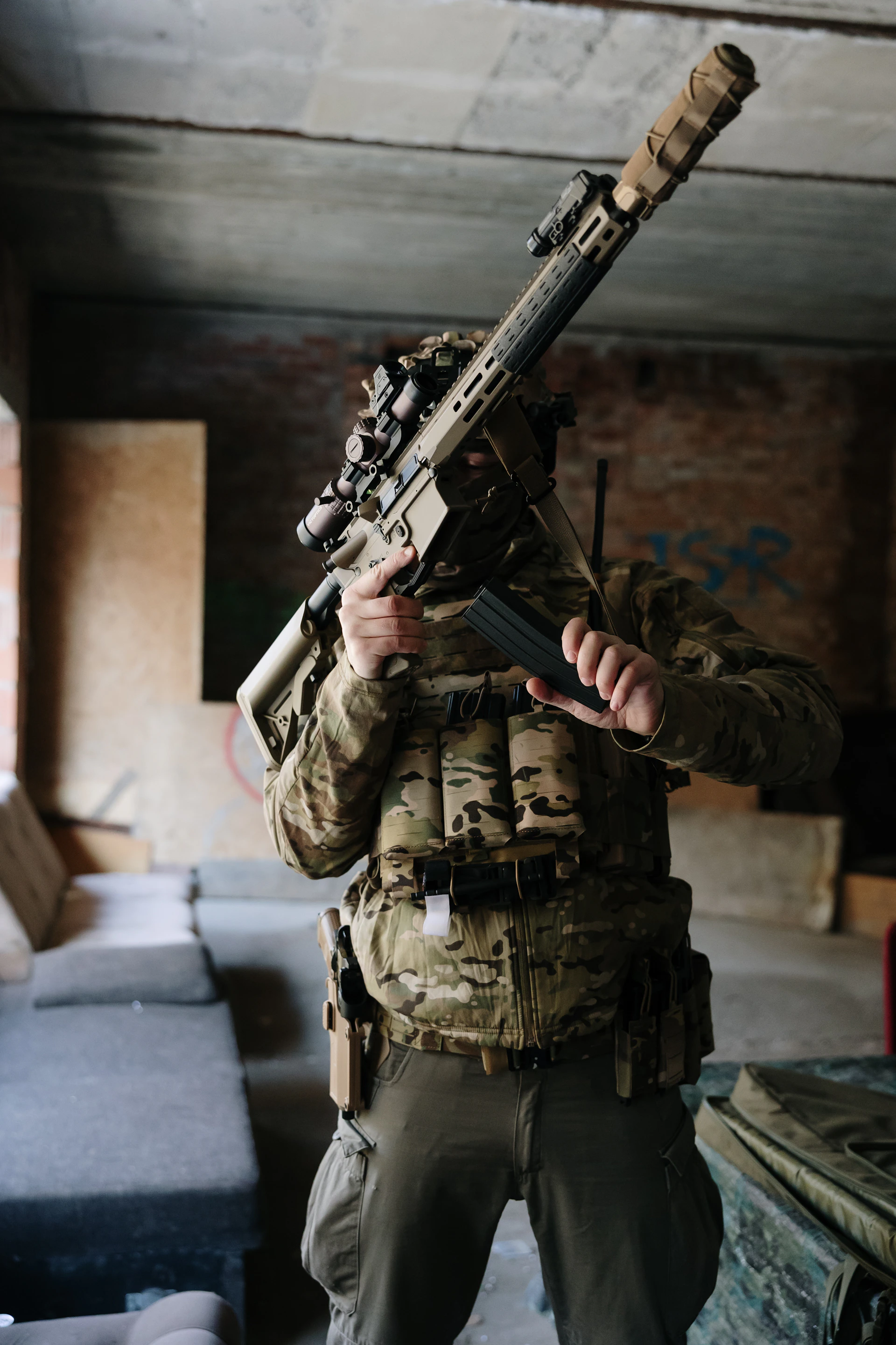 Soldier in tactical gear holding a rifle indoors