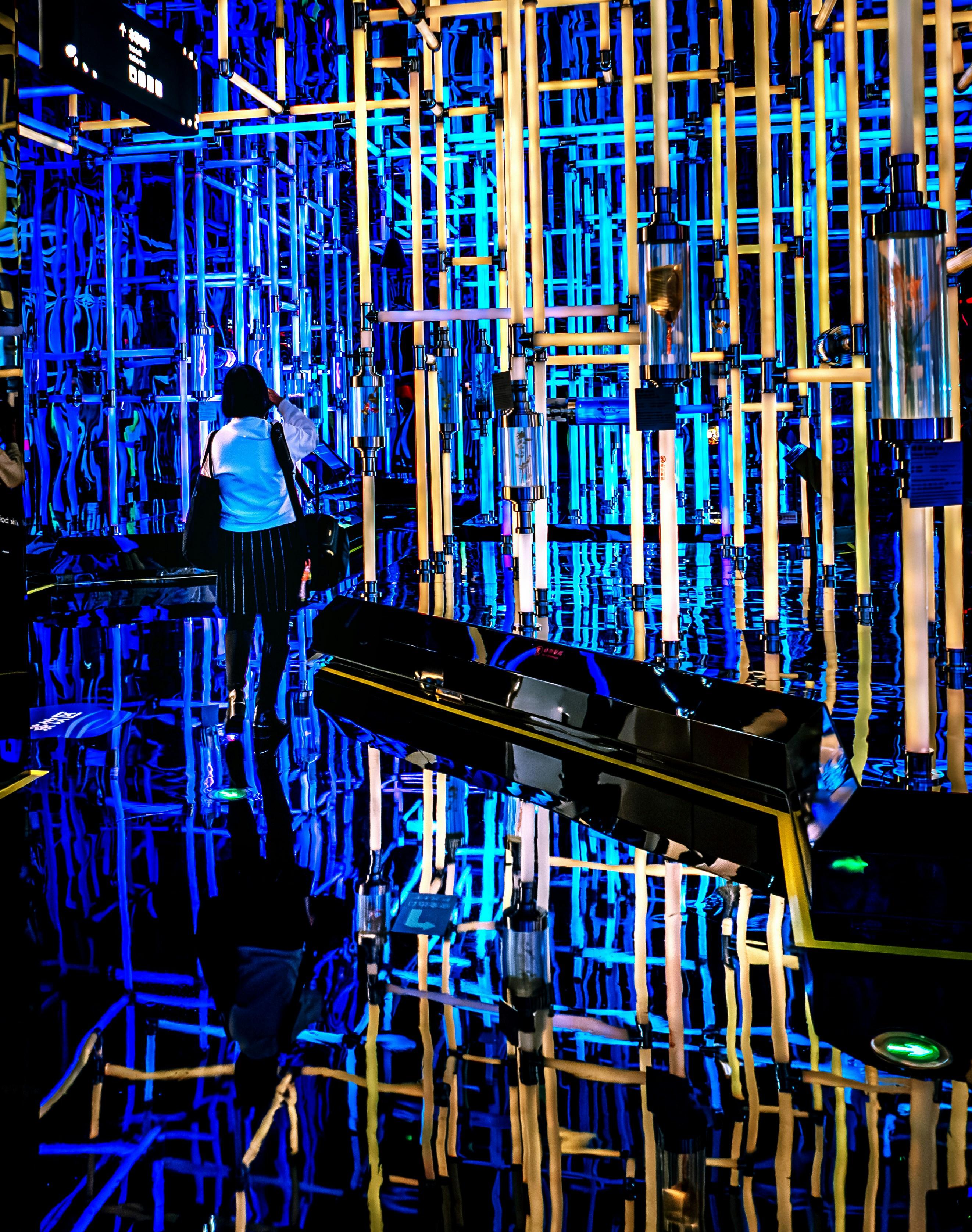 Woman in a blue shirt walks through a neon maze.