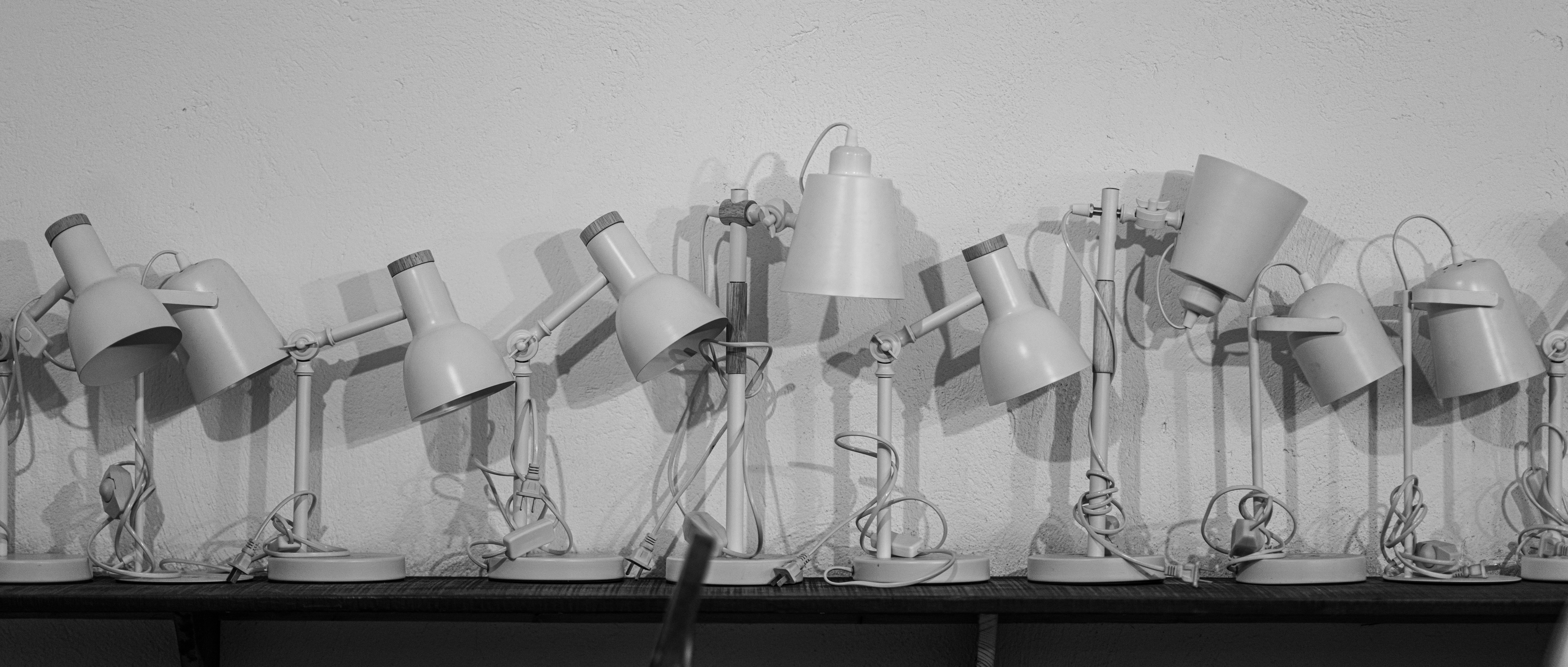 Row of identical desk lamps against a wall