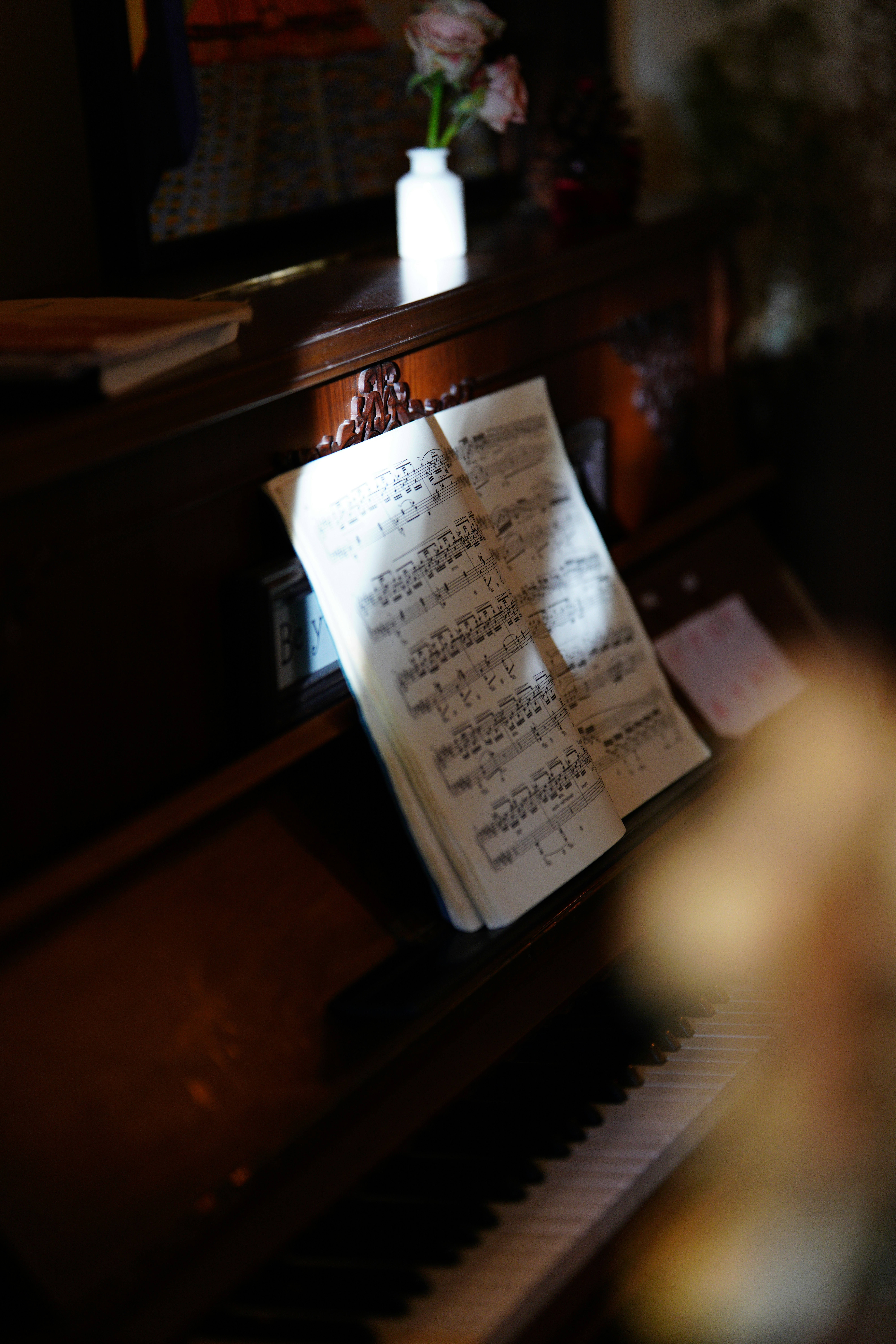 Sheet music rests on a vintage piano keys.