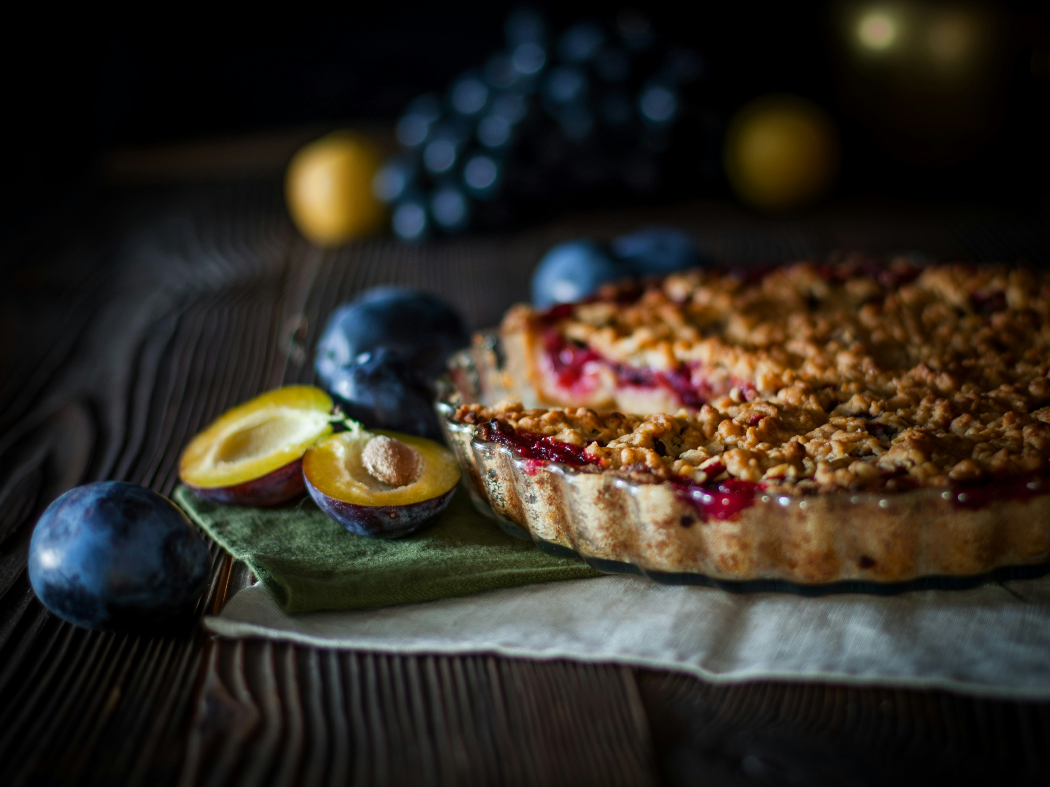 Pflaumencrumble-Tarte mit frischen Pflaumen auf einem Holztisch