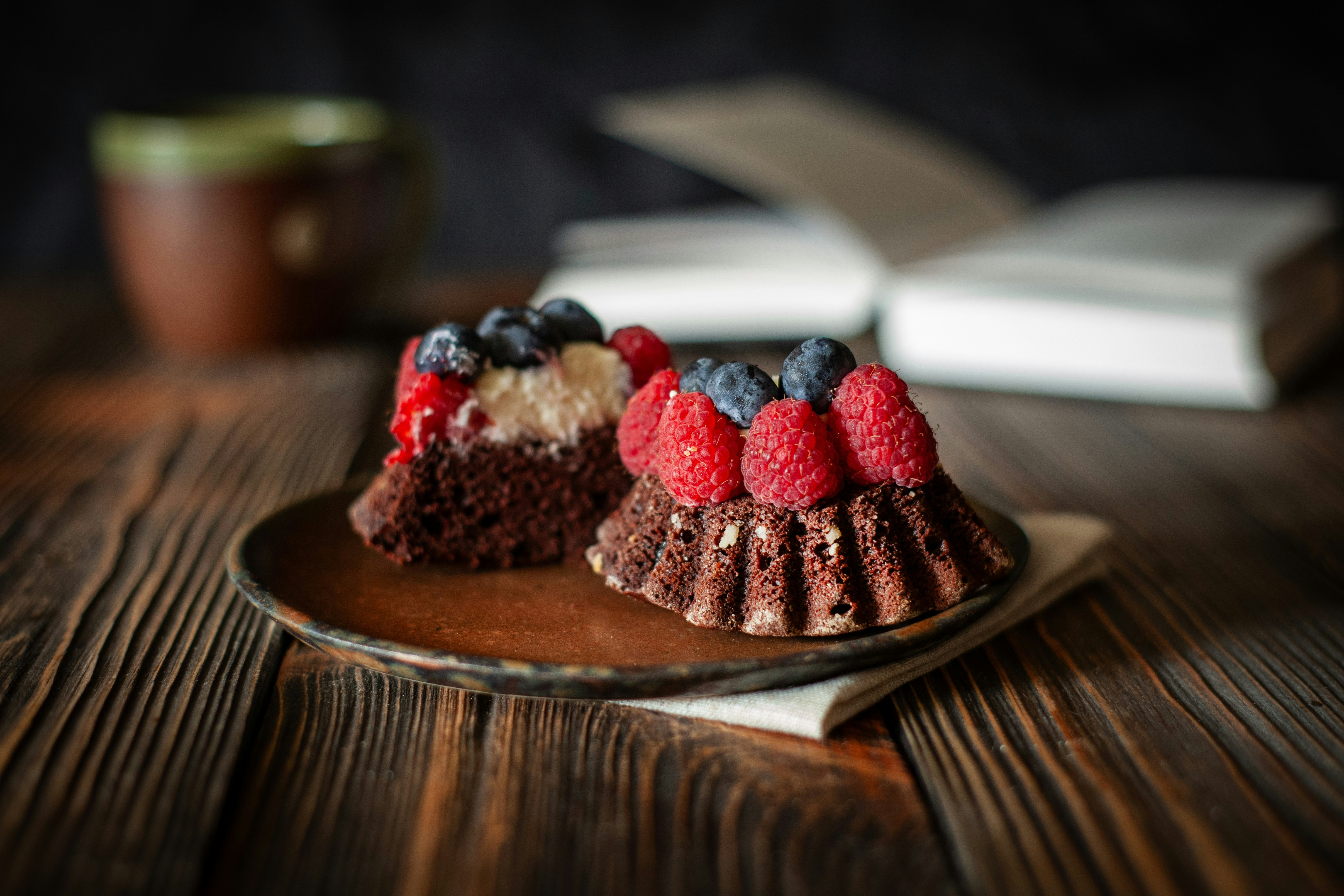 Zwei Schokoladenkuchen mit Beeren auf einem Holztisch.