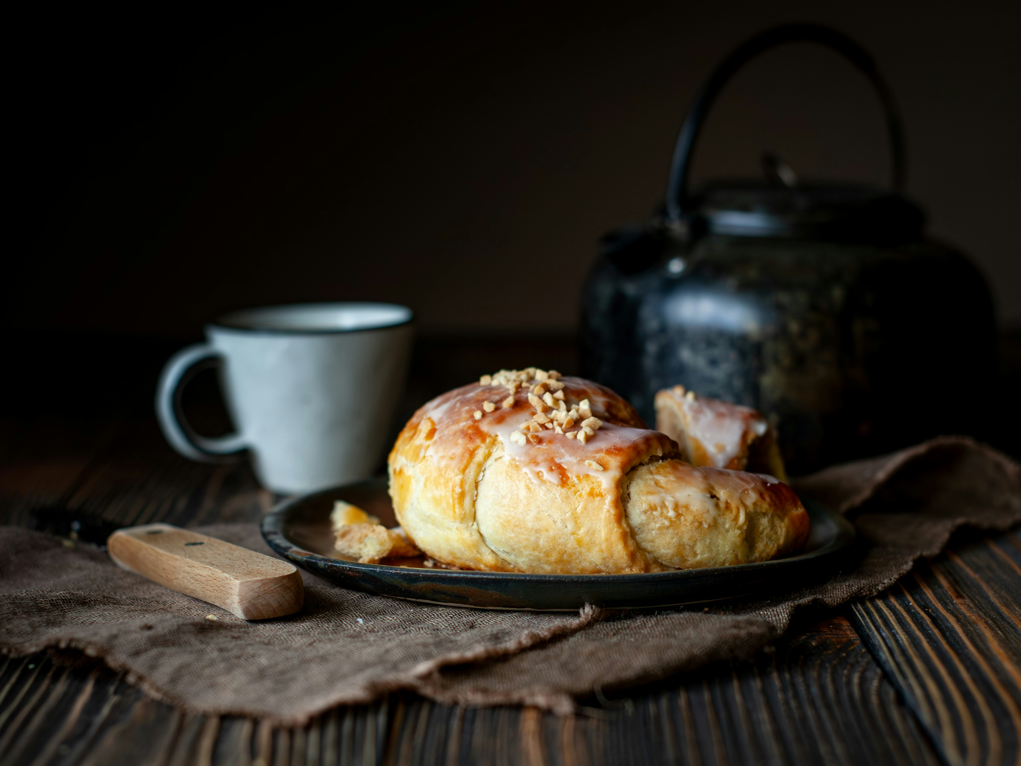 Croissant mit Nüssen und Glasur auf dem Teller mit Tee.