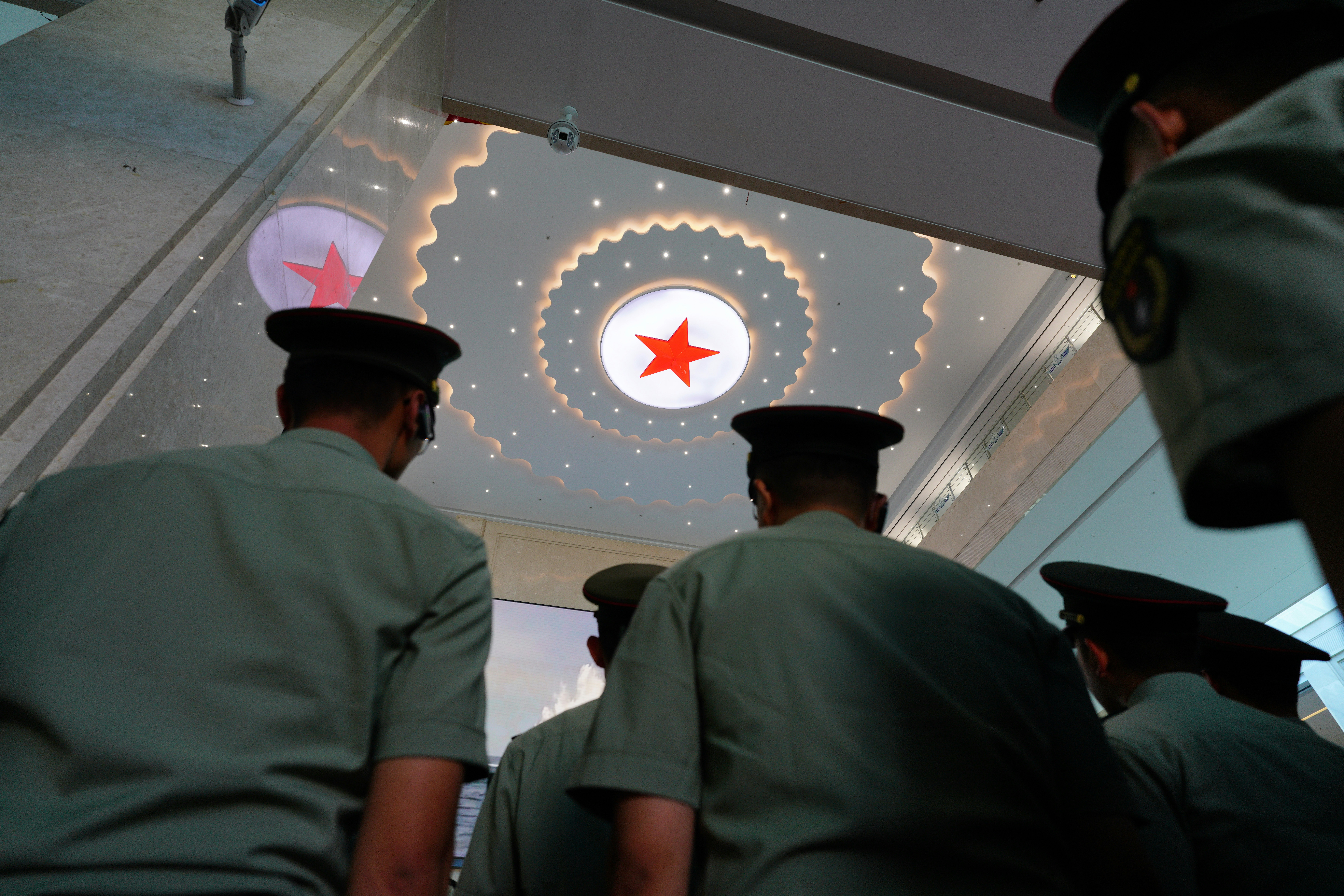 Several soldiers look up at a red star emblem.