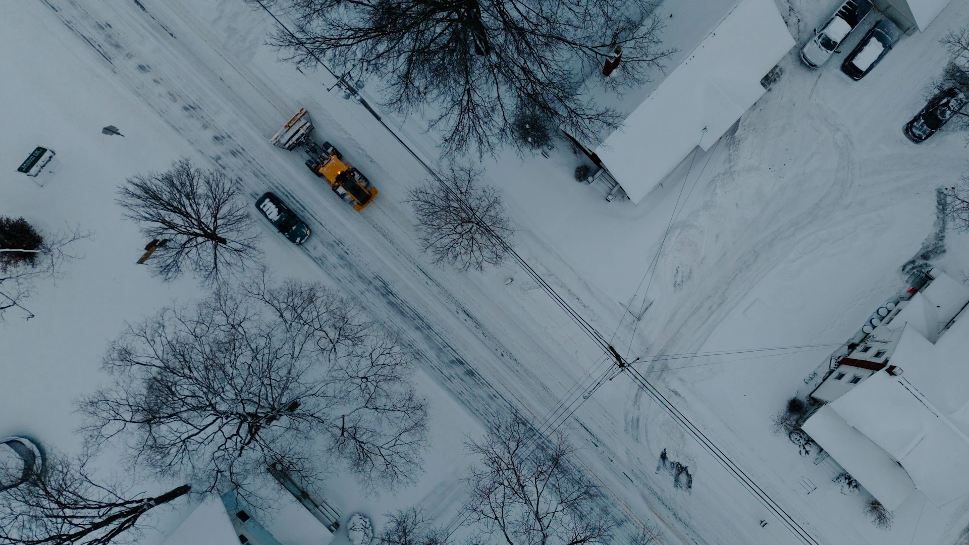 Snowplow clearing a street in a snowy neighborhood