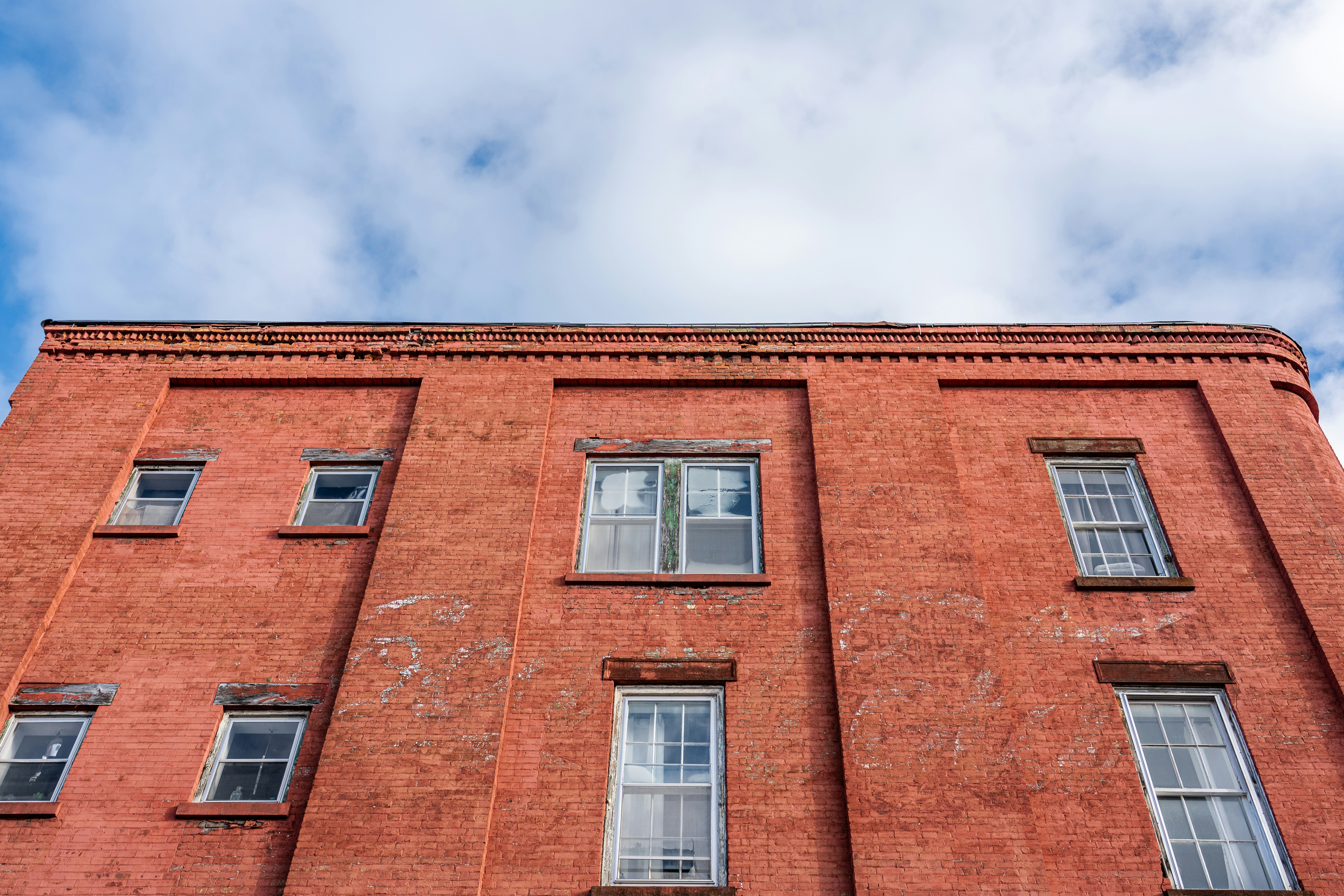 Bâtiment en briques rouges avec des fenêtres blanches contre un ciel nuageux