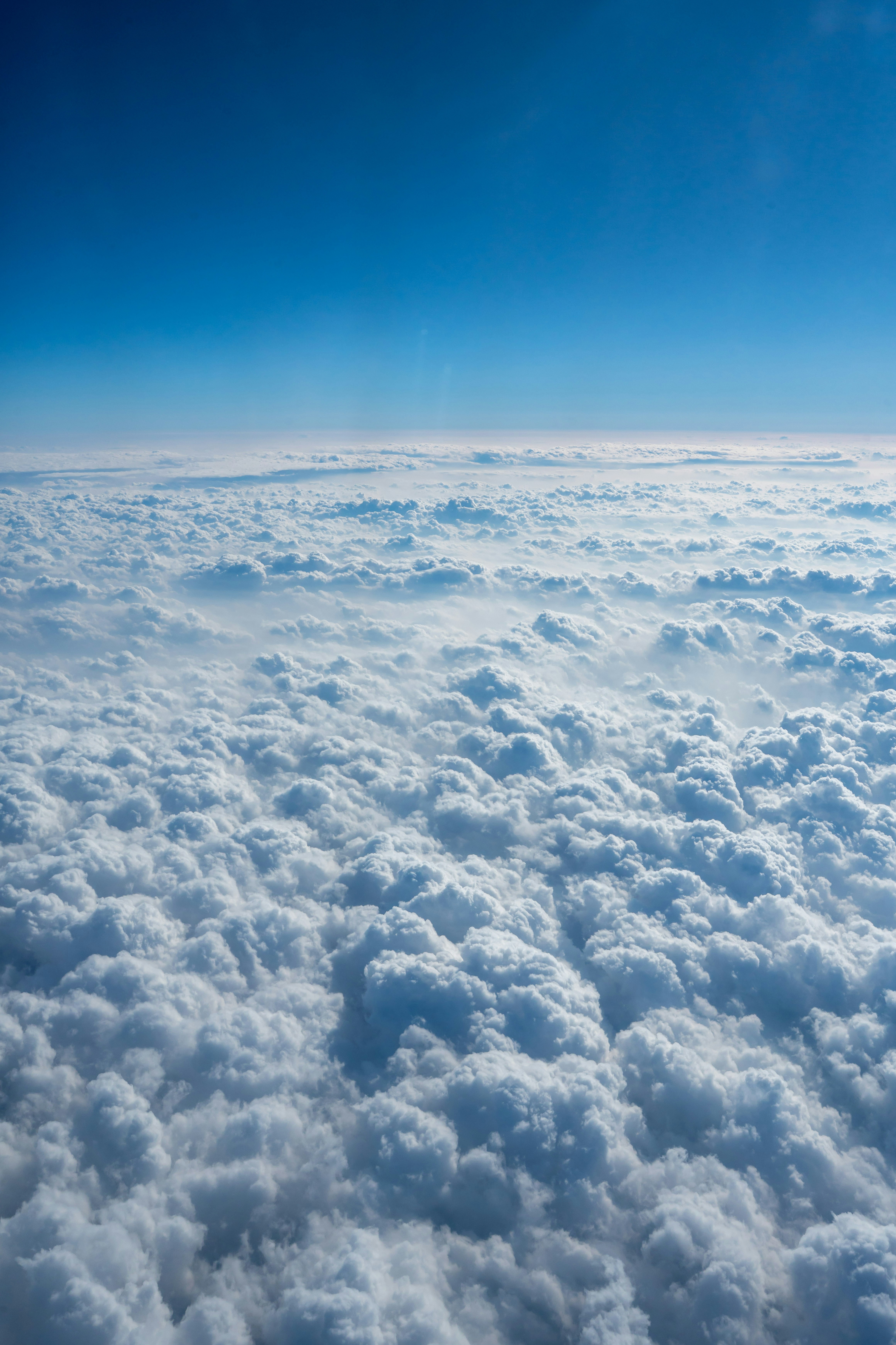 Fluffy white clouds stretch across a clear blue sky