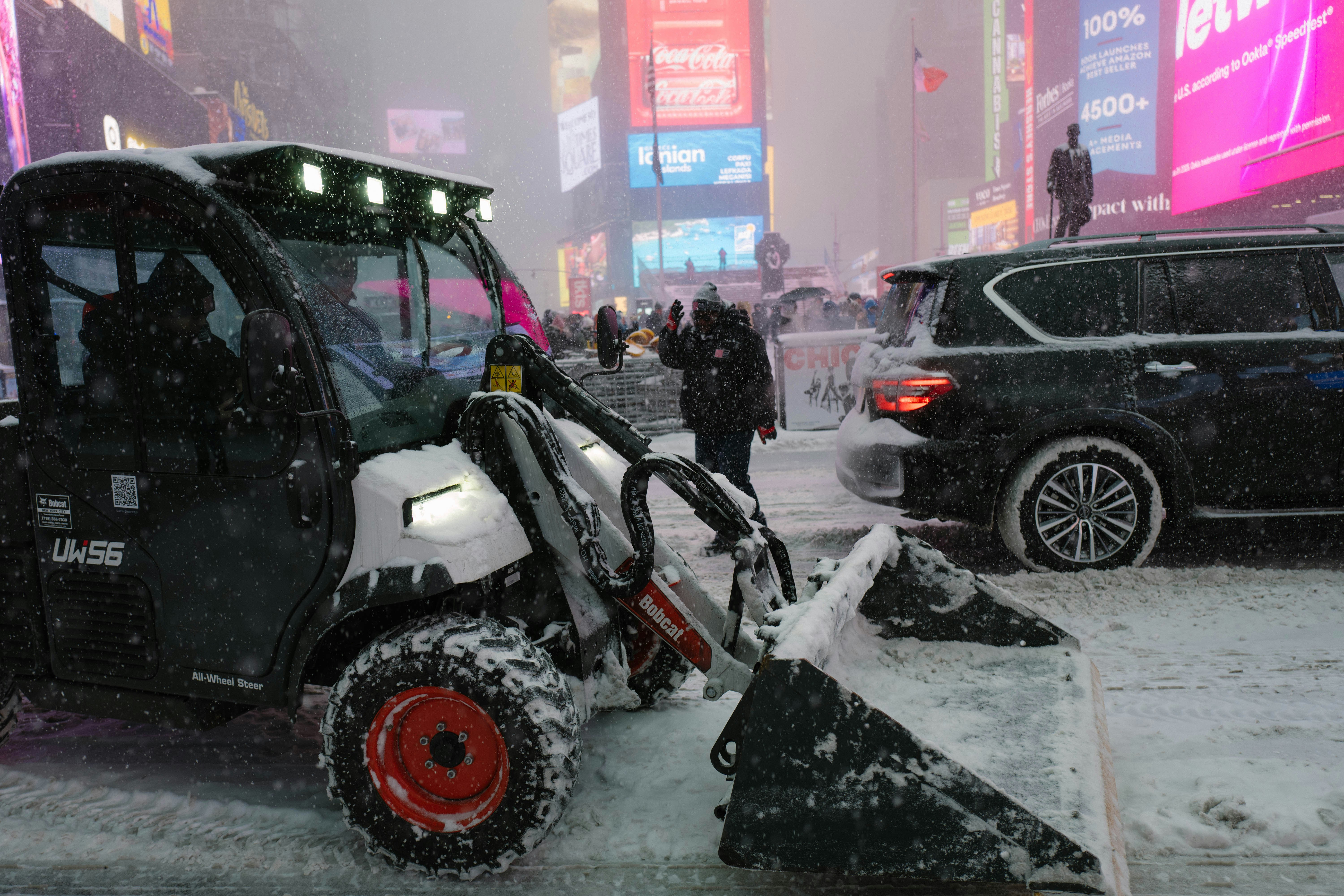 A snowplow clearing snow in a city at night